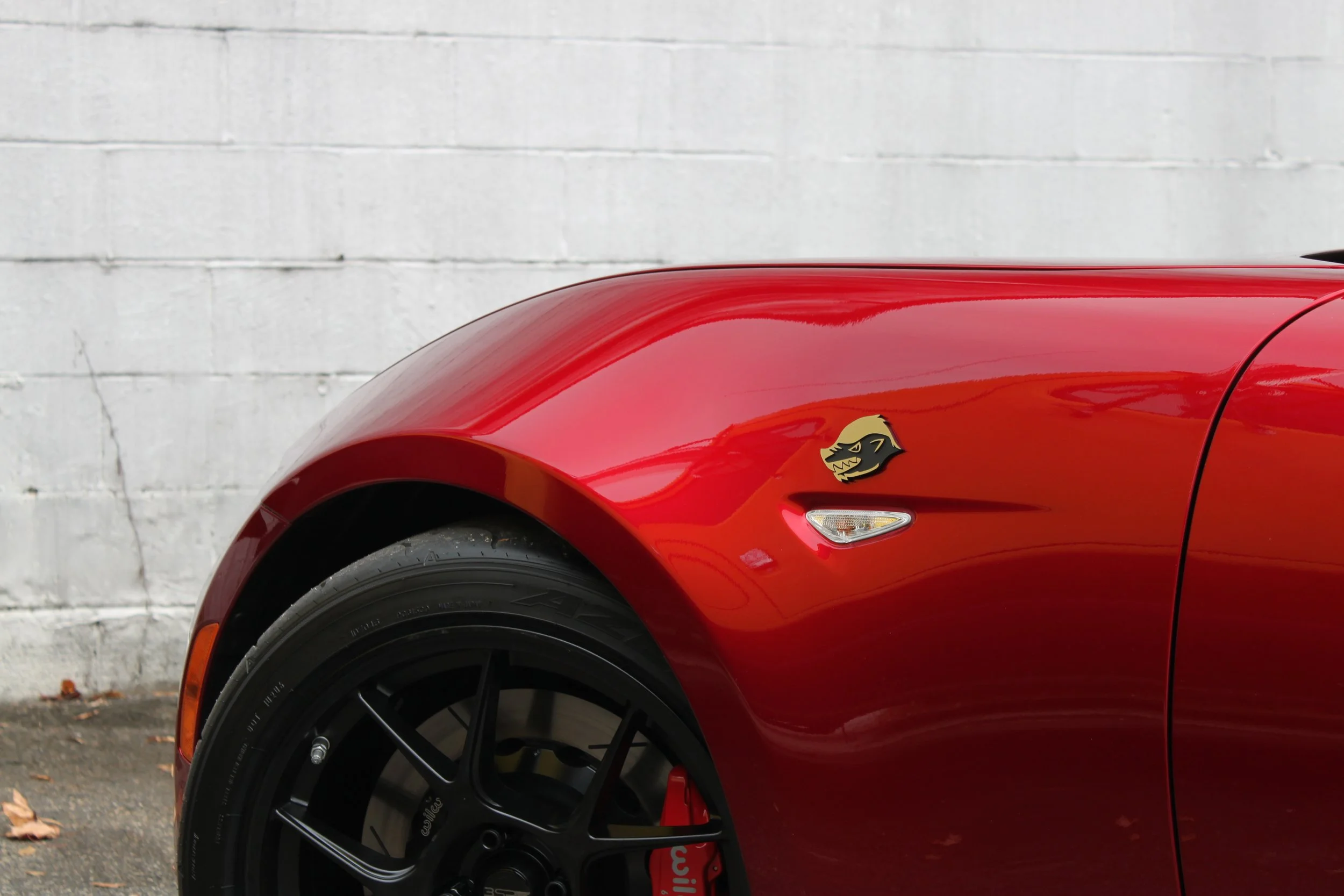 Close-up of the front side of a red sports car with a lightning bolt badge and a stylized angry animal face decal.