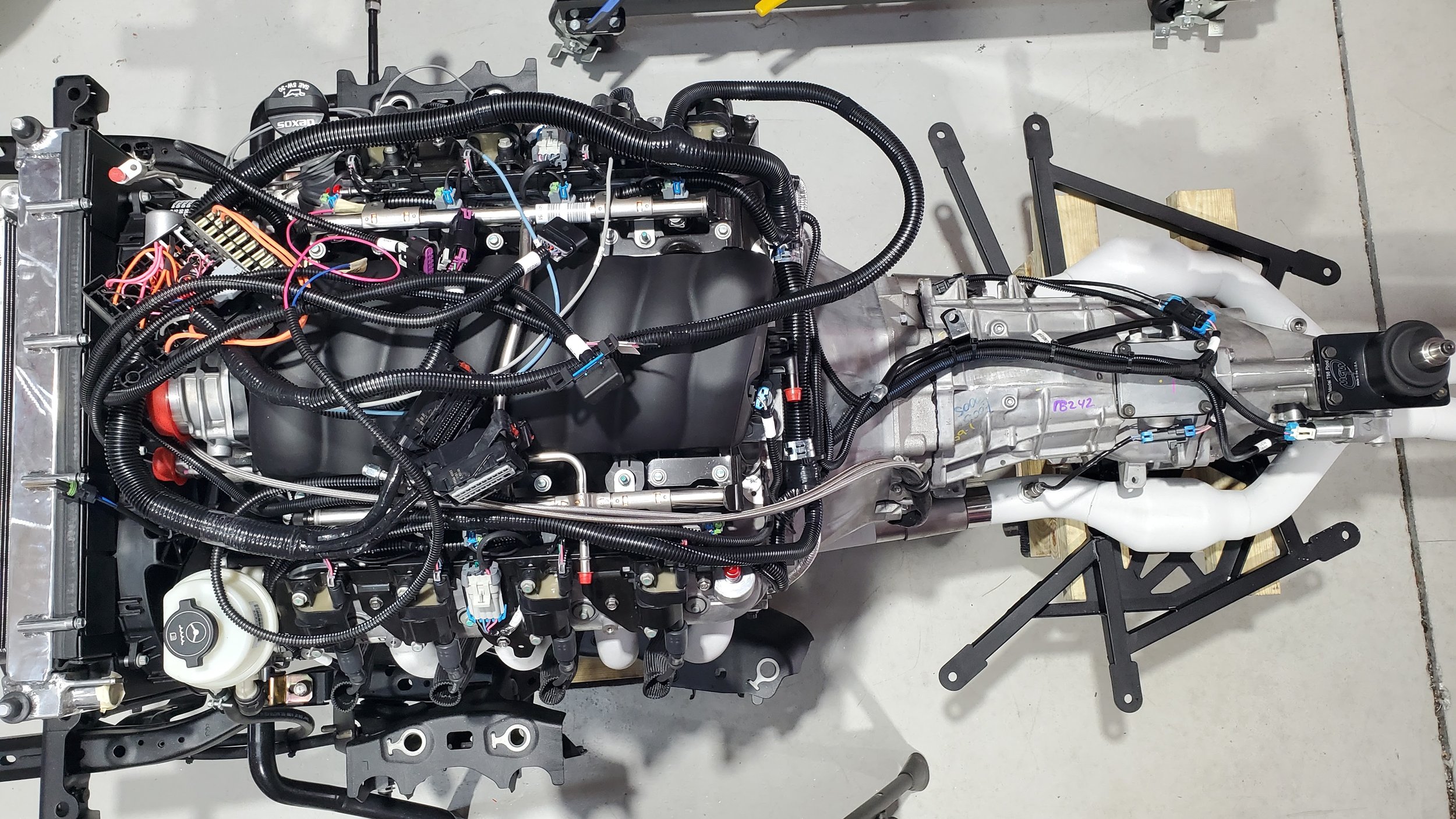 Automobile engine with wired components on a white floor.