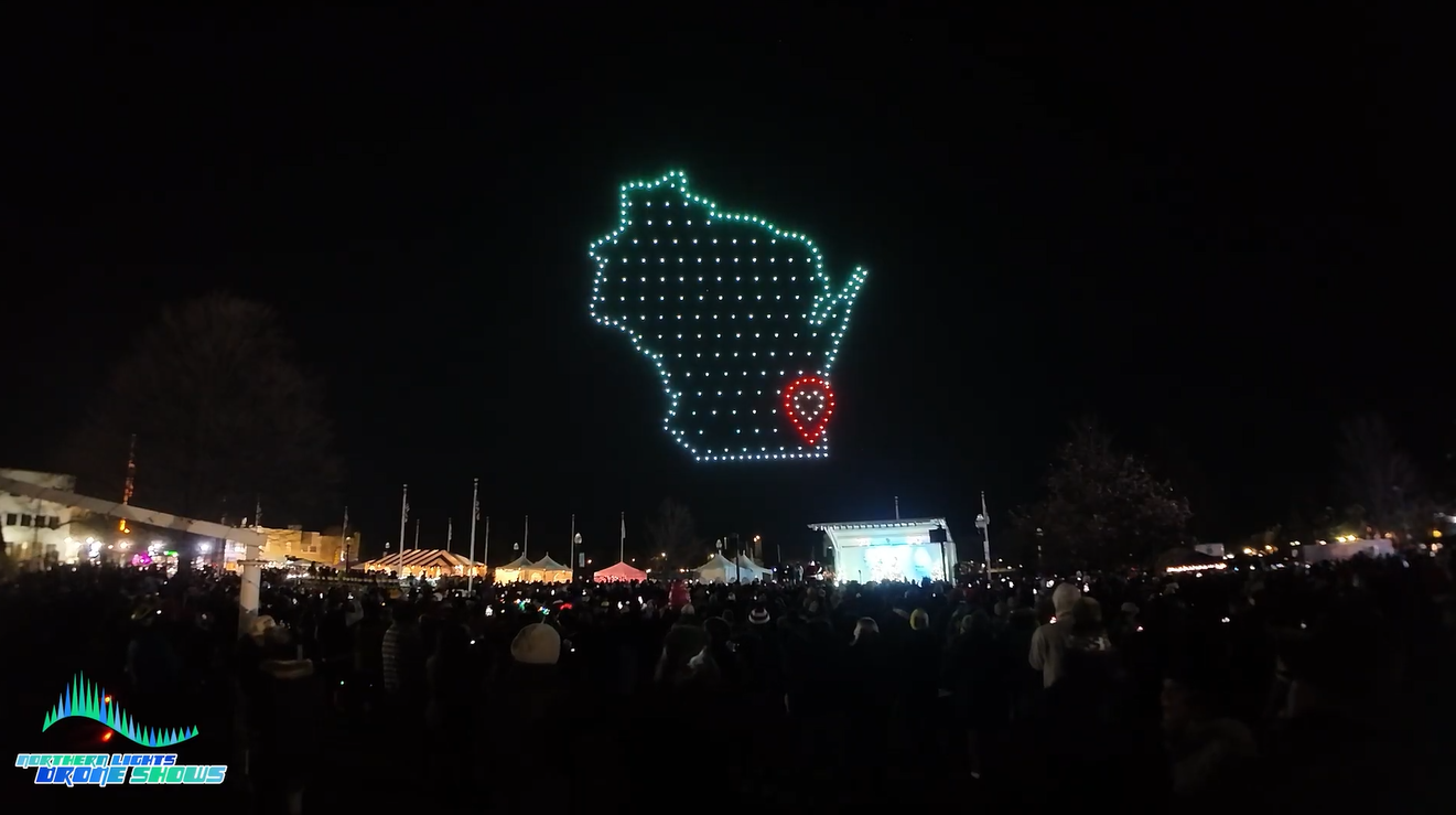 An image depicting a crowd at a festival in Wisconsin watching a drone show from the Northern Lights Drone Shows.