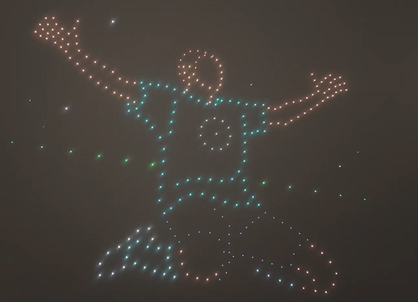 Drones from a drone show depicting a soccer player that just scored a goal and is now celebrating.