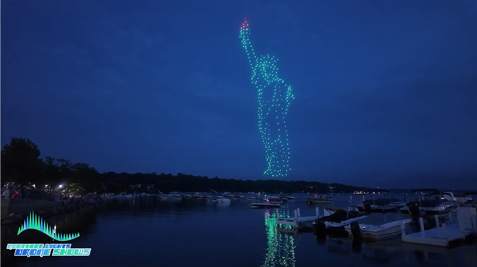 An NLDS drone show depicting the entire statue of liberty above a lake for spectators on boats.