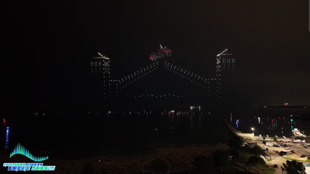 An image from an NLDS drone show depicting a motorcycle jumping across a draw bridge, utilizing pyro drones.