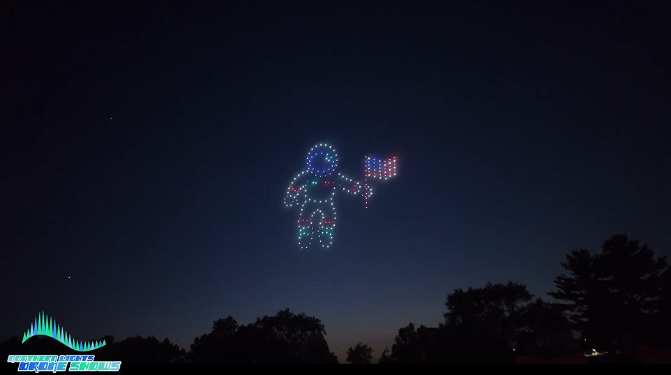 An NLDS drone show depicting a comic astronaut holding an American flag in the sky.