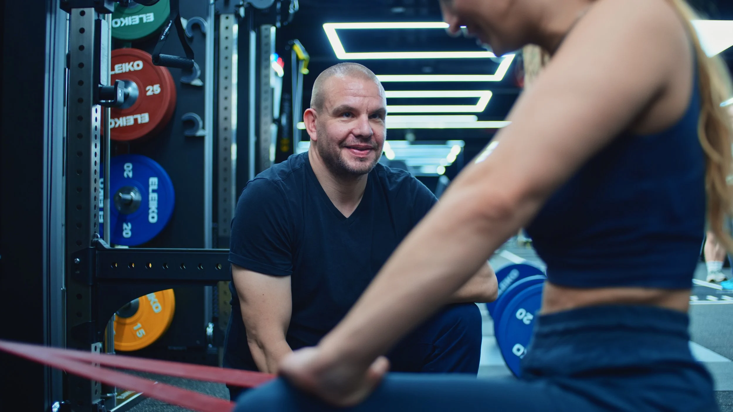 Patient completing tendon loading exercises for shoulder tendinopathy in a rehabilitation gym under the supervision of an exercise rehabilitation specialist.