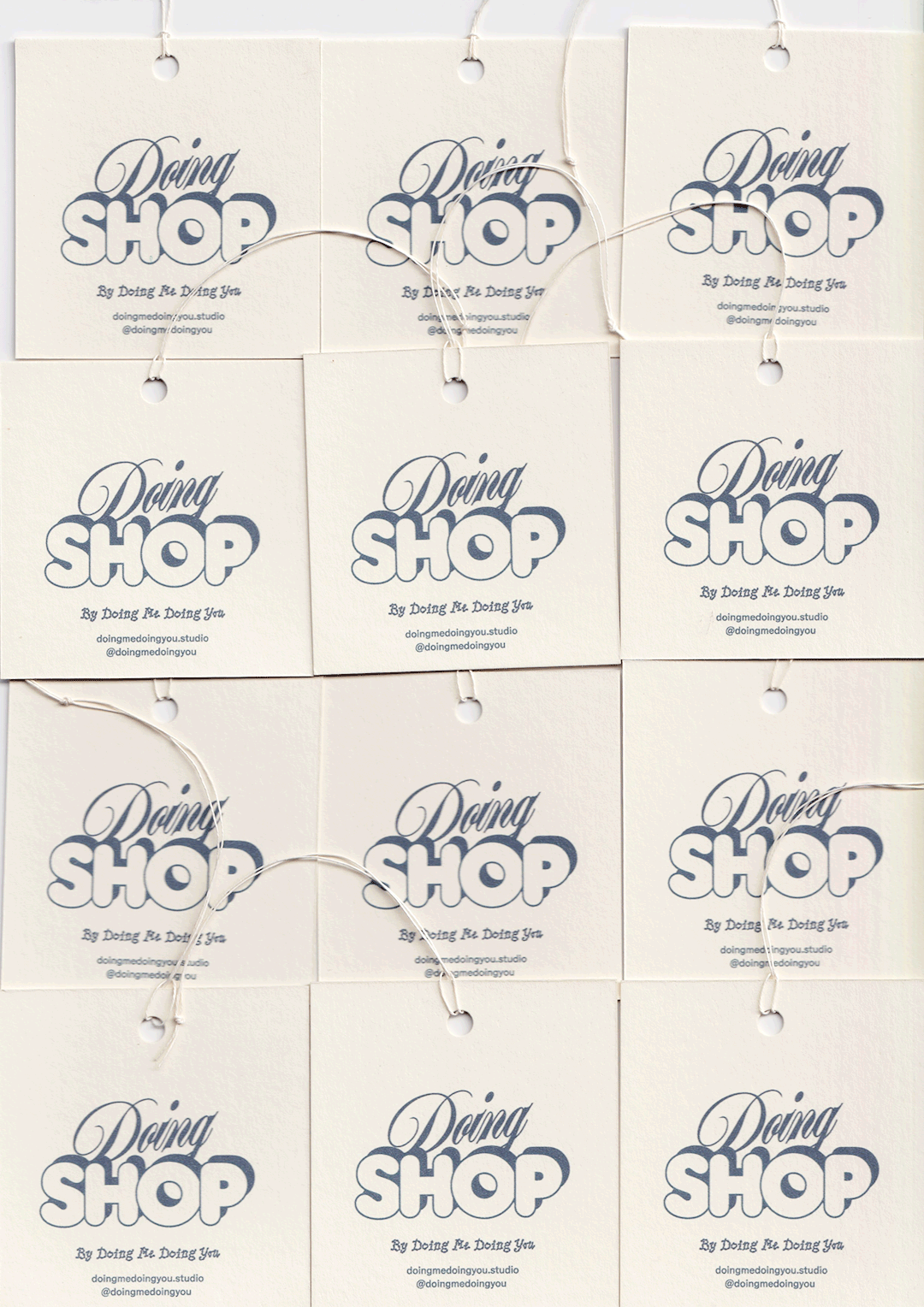 Multiple white squares with 'Doing SHOP' written in stylized blue text, hanging with small white strings against a white background.