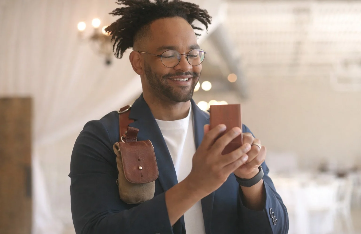 John Branch smiling while holding a phone during a behind-the-scenes moment.