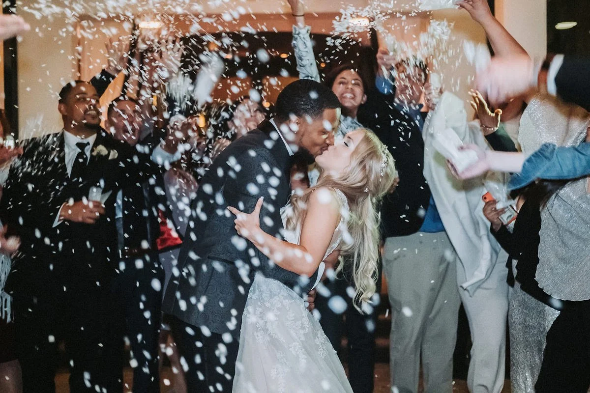 Newly married couple kissing during a confetti exit.