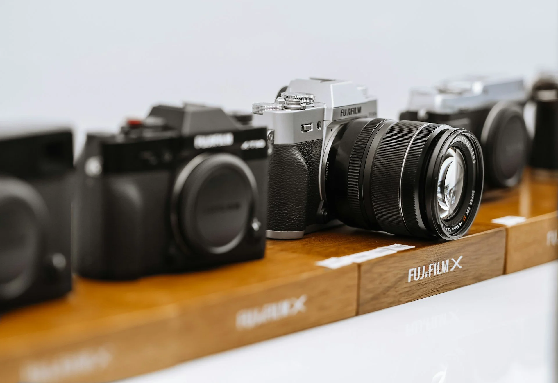 Fujifilm mirrorless cameras displayed with photography lenses.
