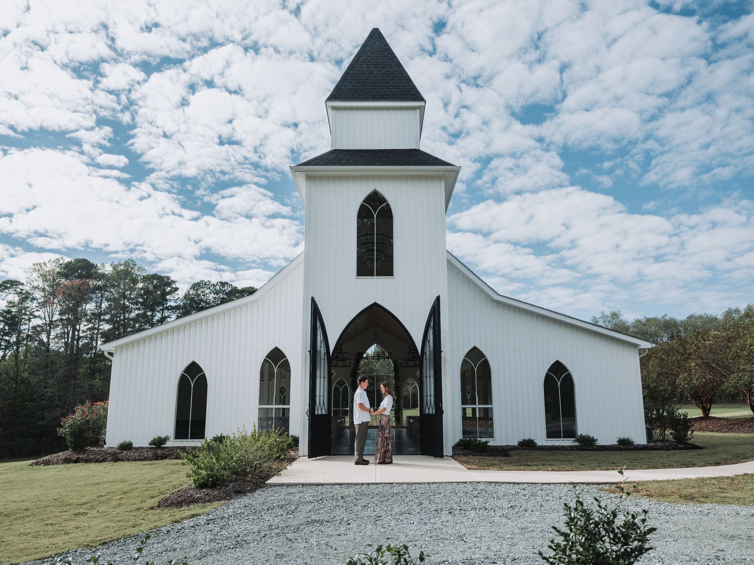 Couple outside a white chapel during an engagement photography session.