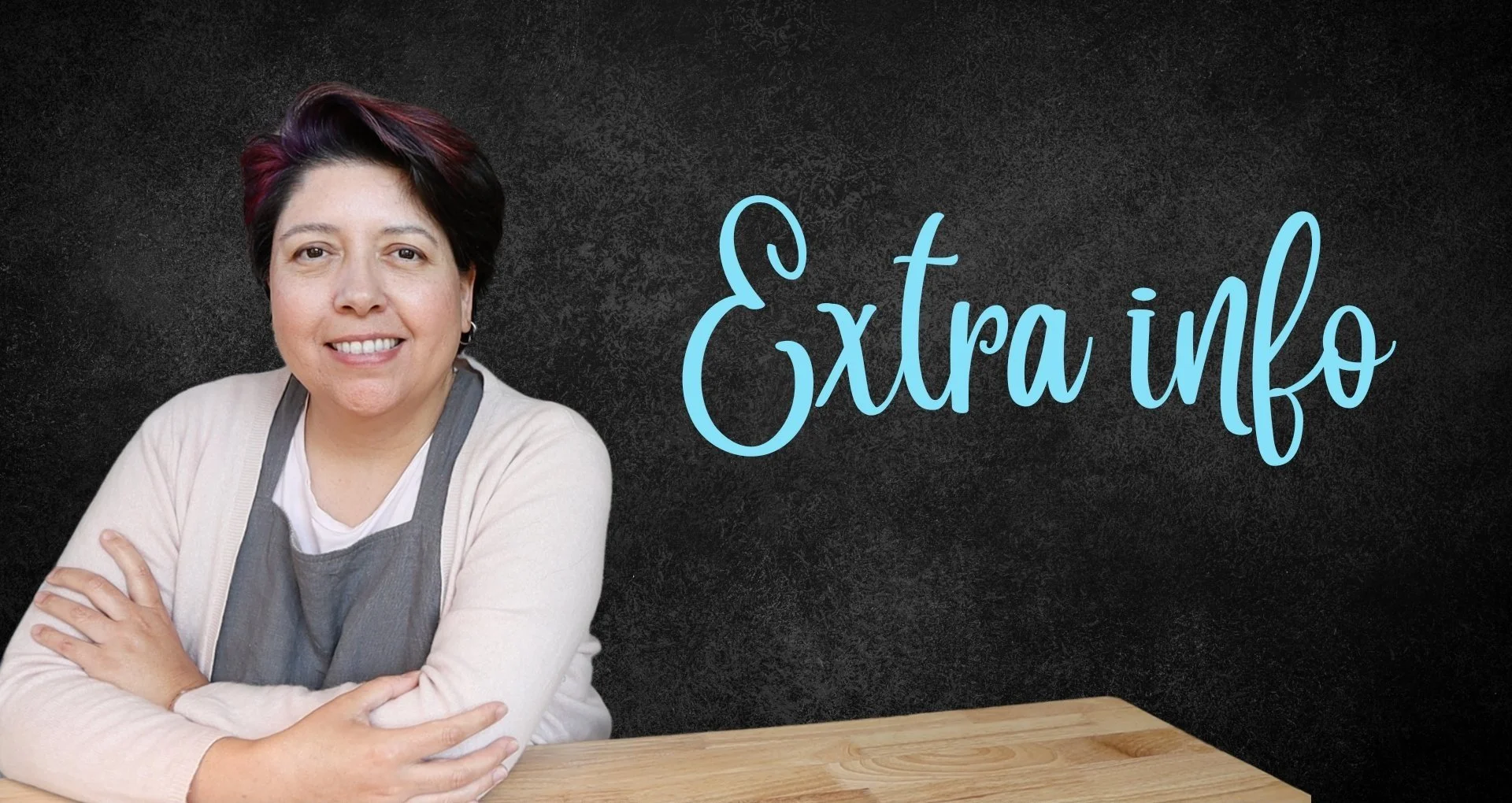 Person smiling with folded arms, wearing a gray apron and beige sweater against a black background with the text "Extra info."
