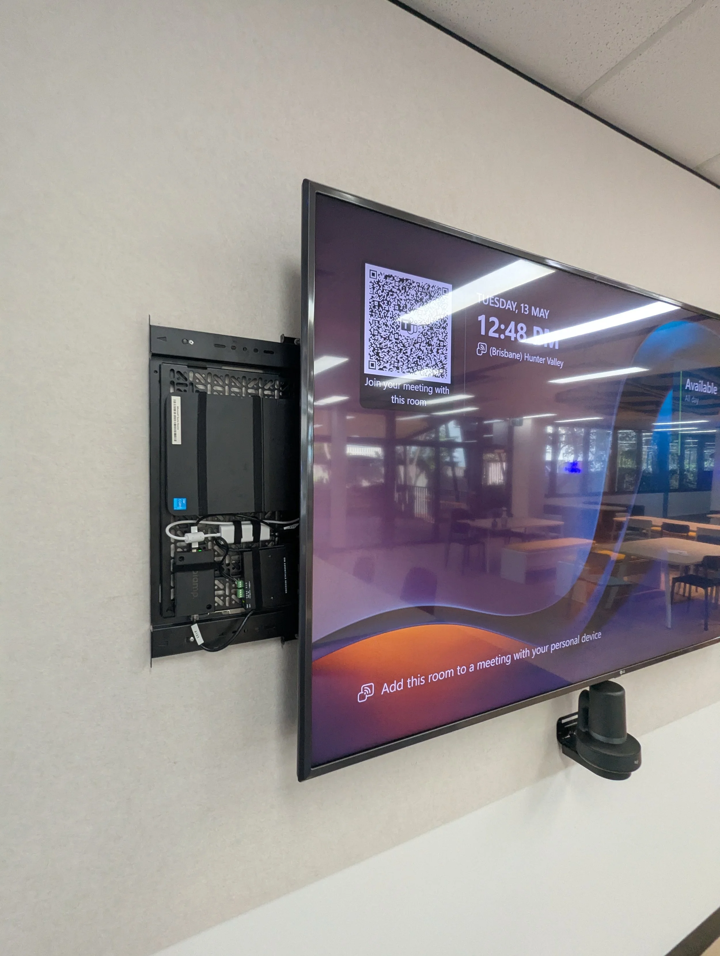 Wall-mounted meeting room display with integrated conferencing interface and room booking system.