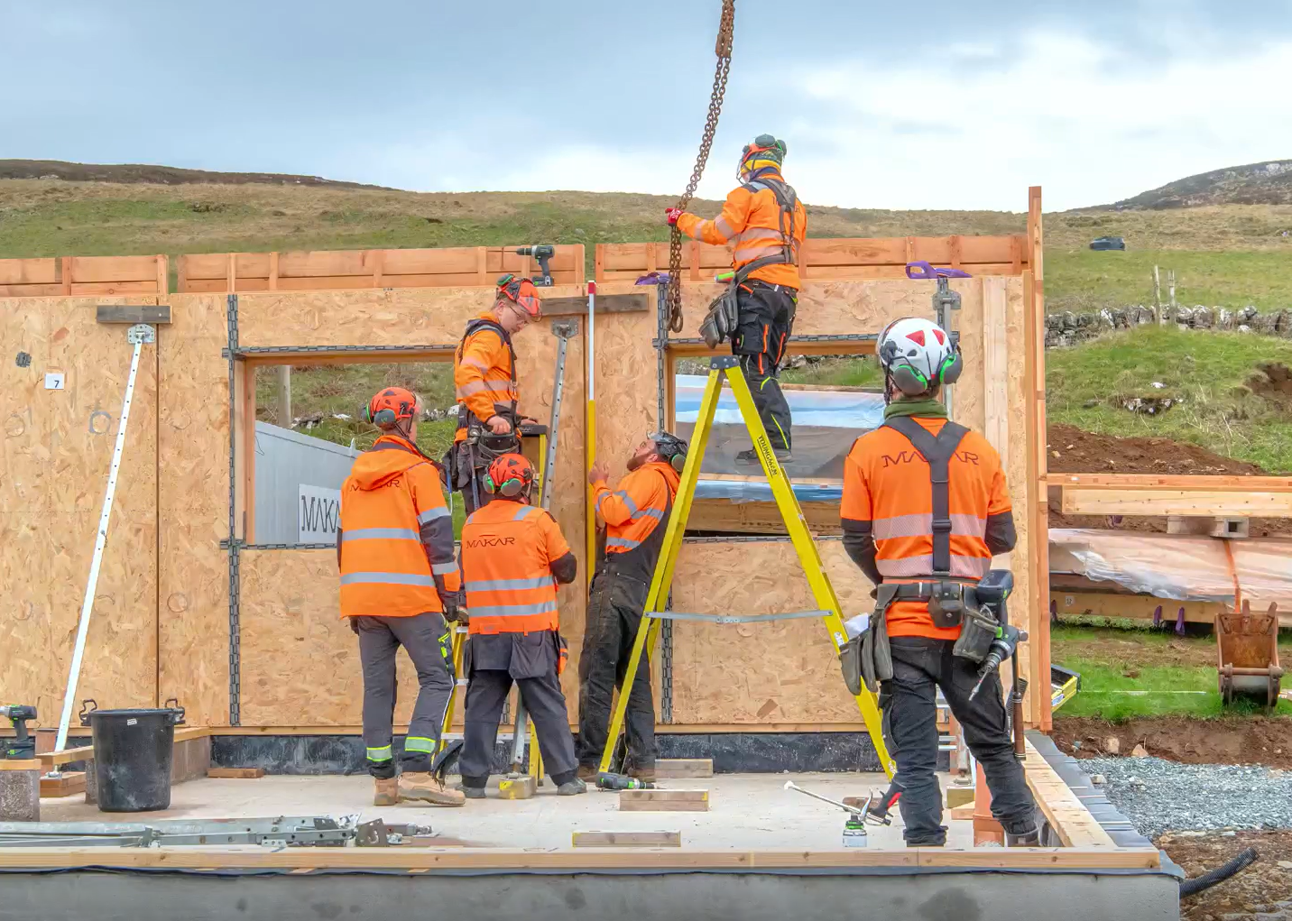 Construction workers assembling a wall on a building site outdoors.