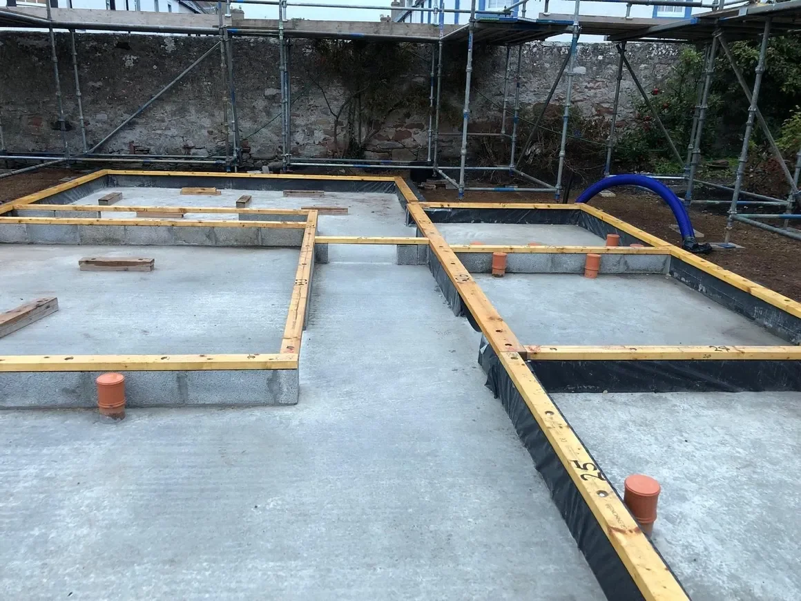 Construction site with concrete foundation and wooden framing for a building.
