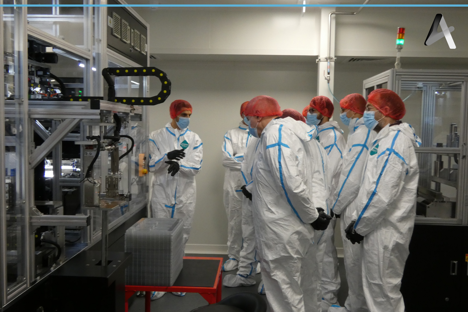 Groupe de personnes en tenue de protection dans un laboratoire entouré de machines et d'équipements scientifiques