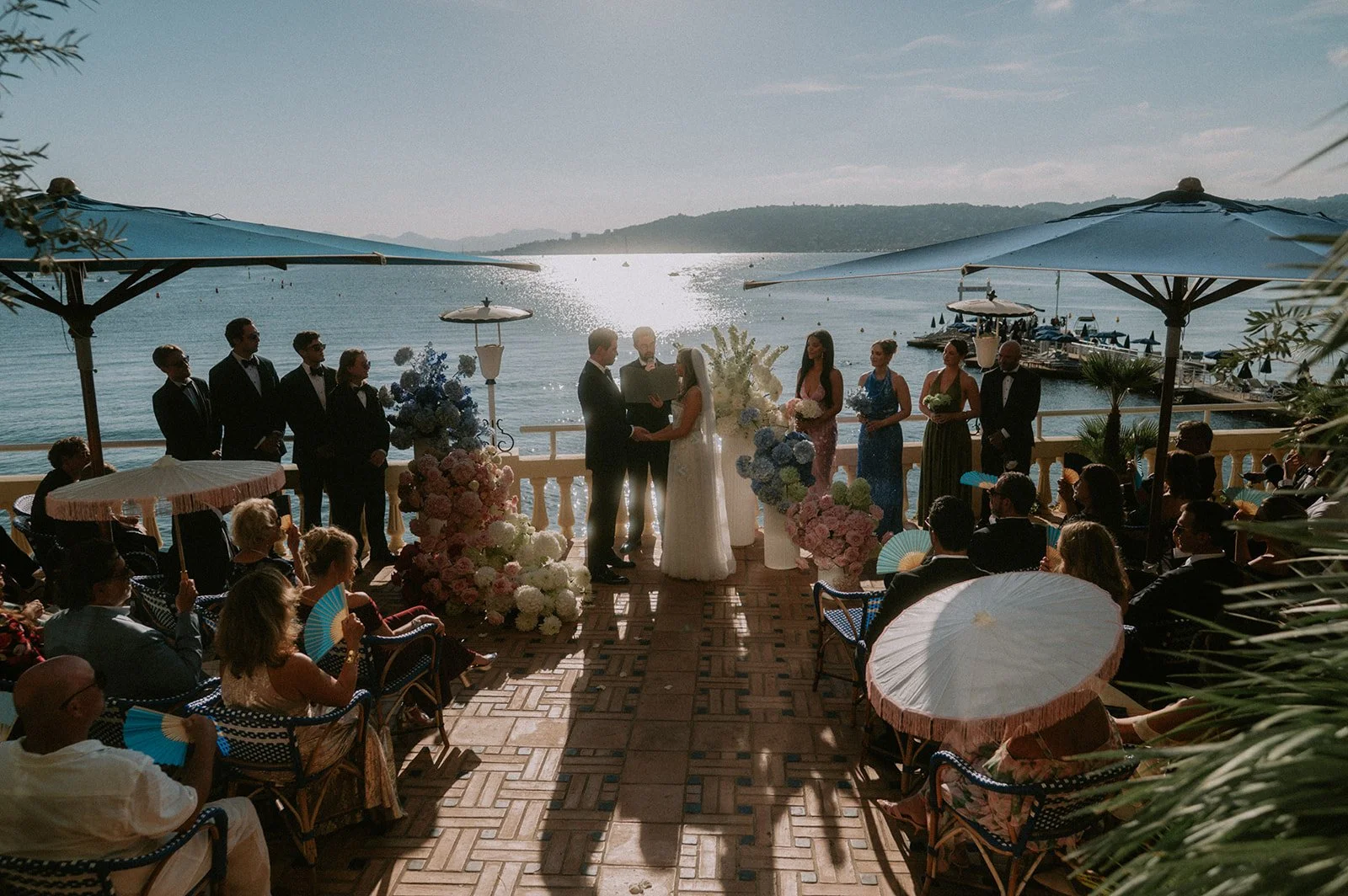 Wedding ceremony on a seaside terrace in Antibes, couple at the altar framed by blue, pink and white flower installations