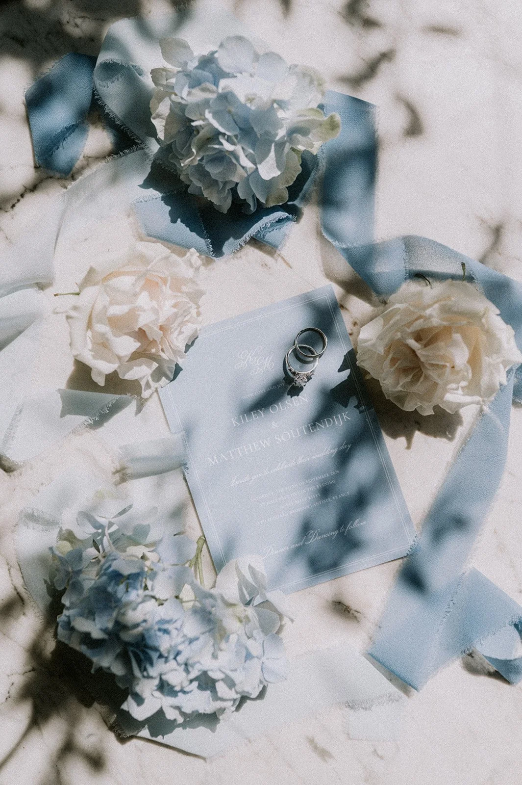 Wedding invitation flat-lay with blue ribbon, hydrangea, blush roses and rings, by wedding florist GRÖNT, French Riviera