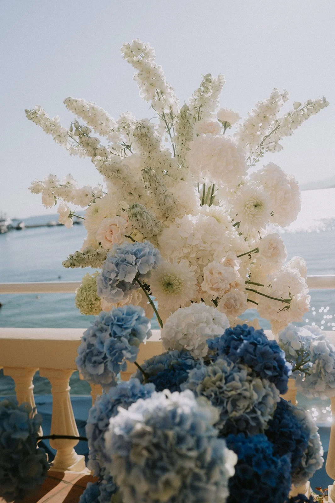 White delphinium, chrysanthemum and blue hydrangea wedding flowers at a sea-view balustrade, Côte d’Azur