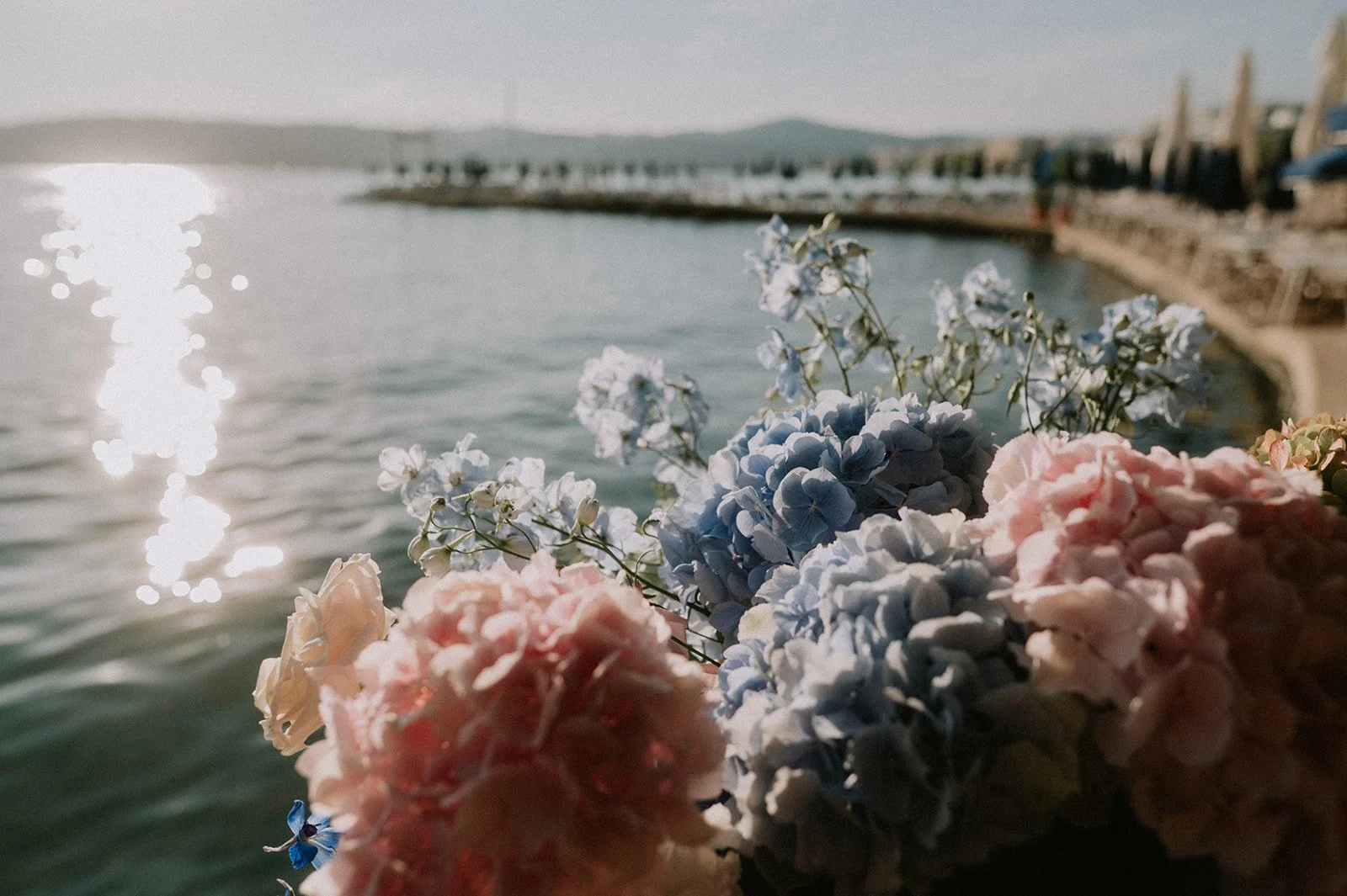 Close-up of blue and pink hydrangea wedding flowers with the sea sparkling behind, Côte d’Azur