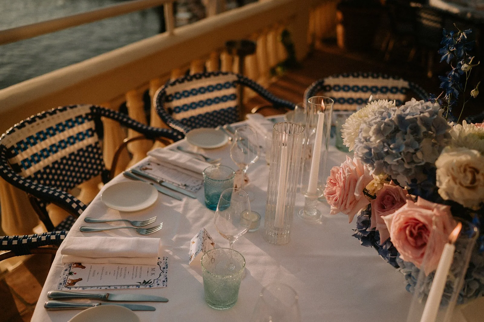 Wedding reception table with a low garden rose and hydrangea centrepiece, fluted glass candle holders and menus, French Riviera