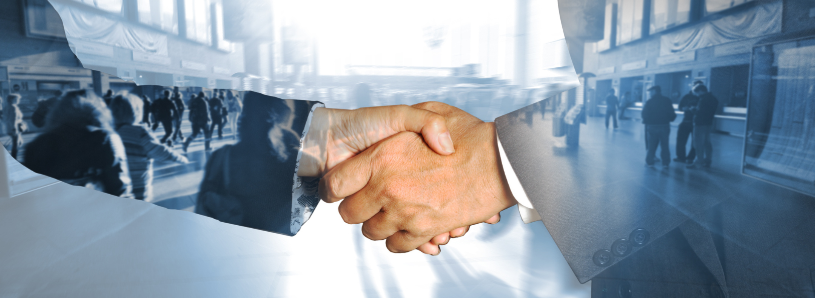 Handshake zwischen zwei Personen vor einem Bahnhof im Hintergrund mit wartenden Menschen