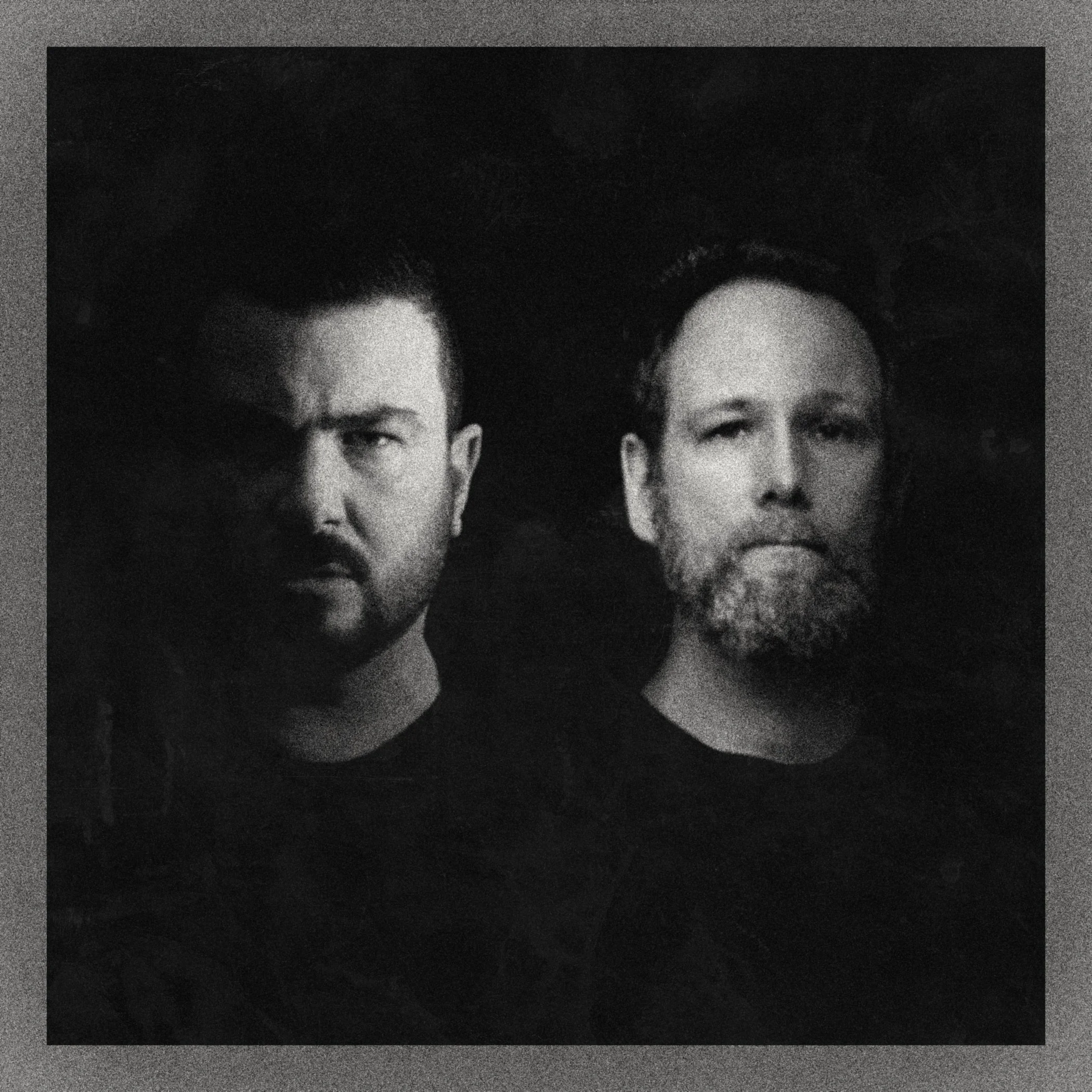 Black and white portrait of two men with intense expressions.