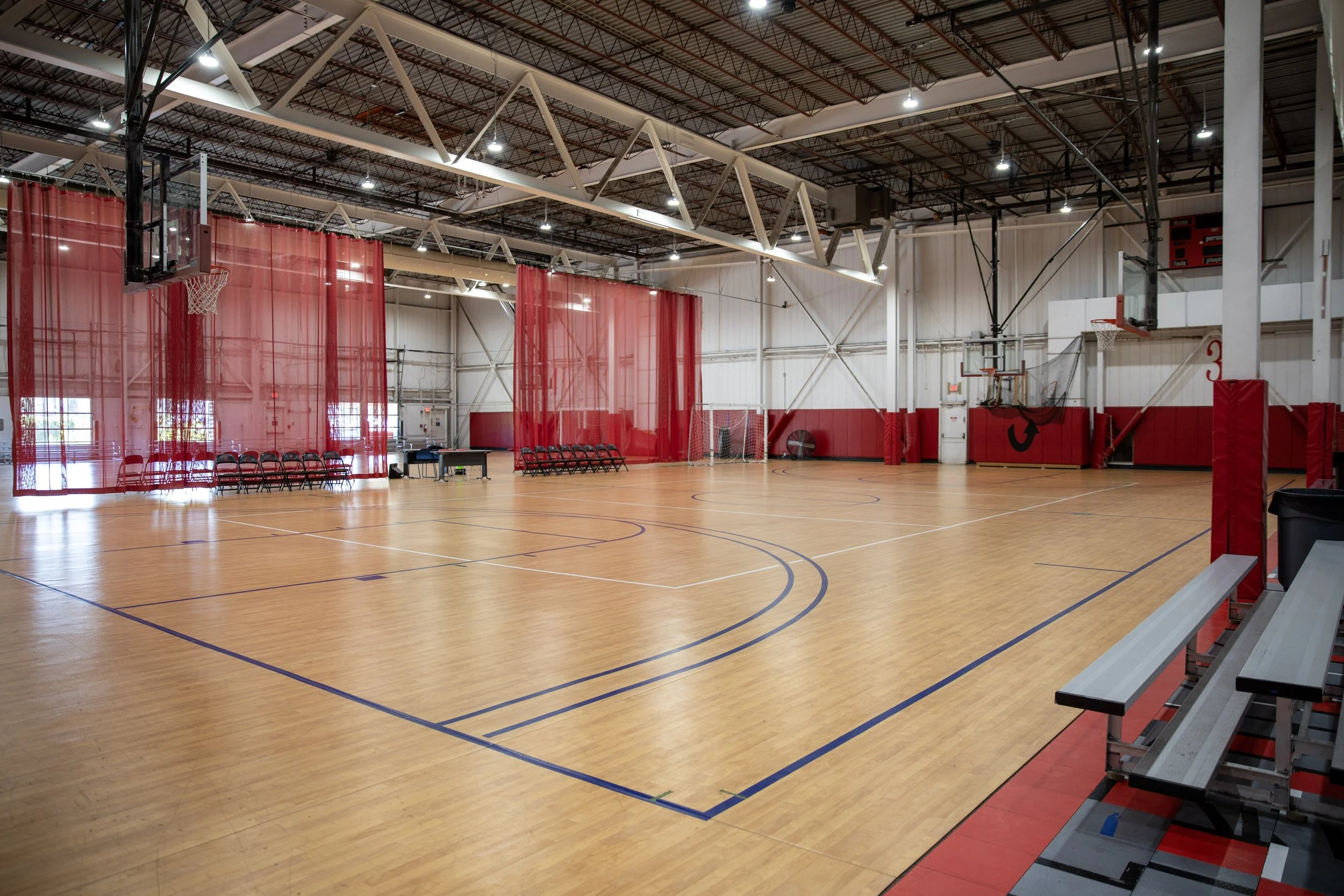 An indoor basketball gymnasium with polished floors, multiple basketball hoops in Richmond, VA.