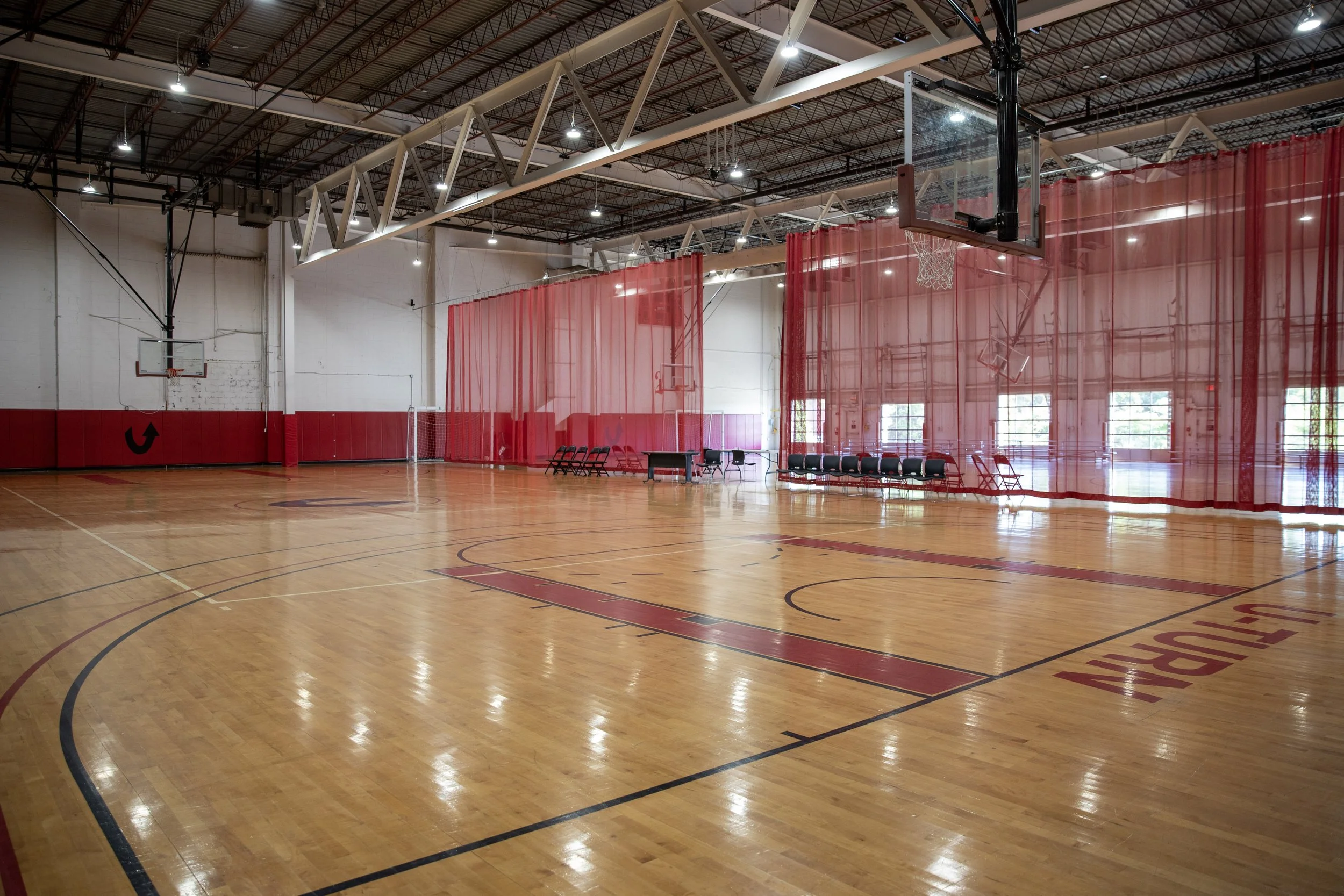 An indoor basketball court with polished wooden floors, and basketball hoops with scoreboards in Richmond, Virginia.