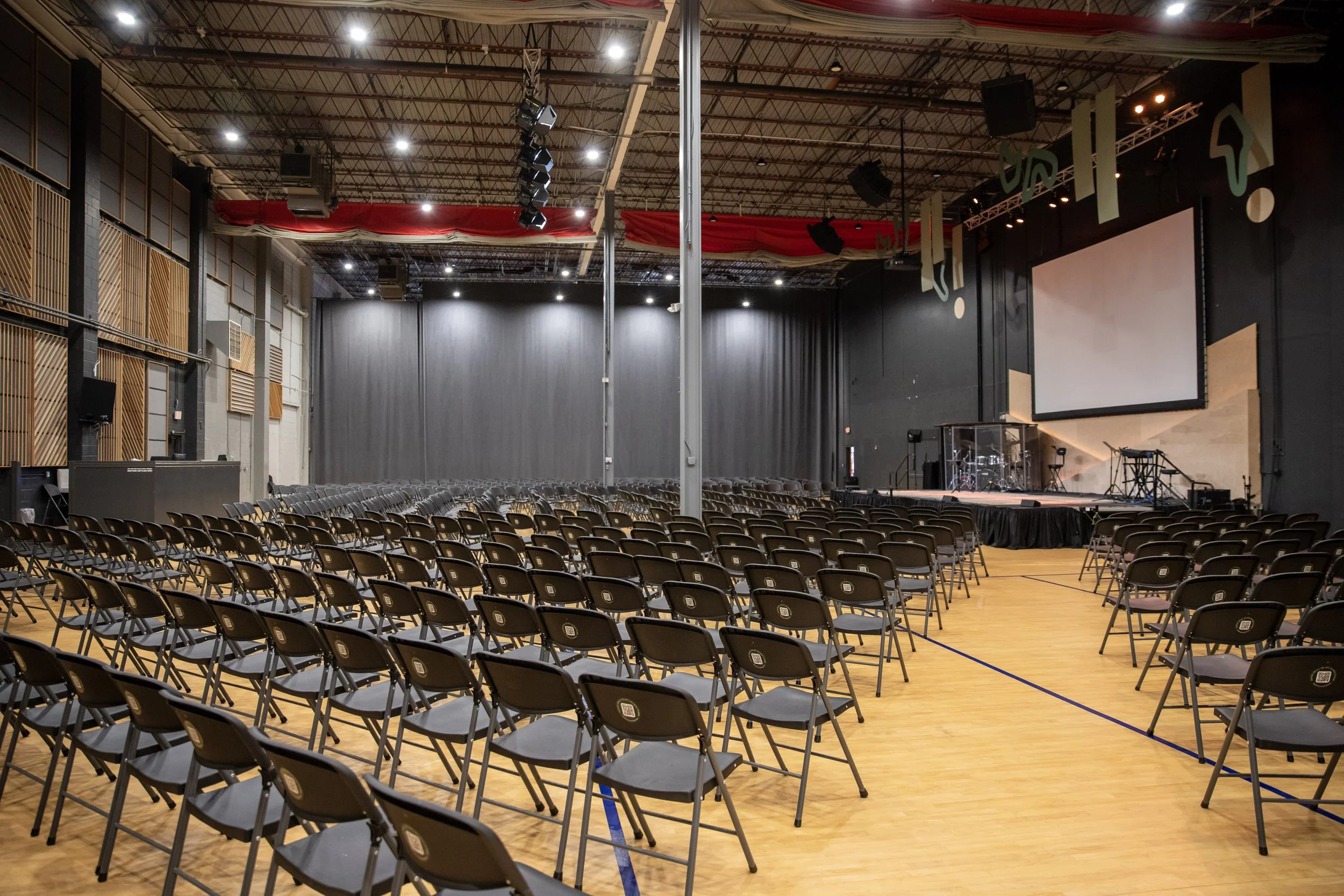 An auditorium with rows of black chairs, a stage with musical instruments, large video screen, and ceiling-mounted speakers, ready for a performance or event in Richmond, Virginia.