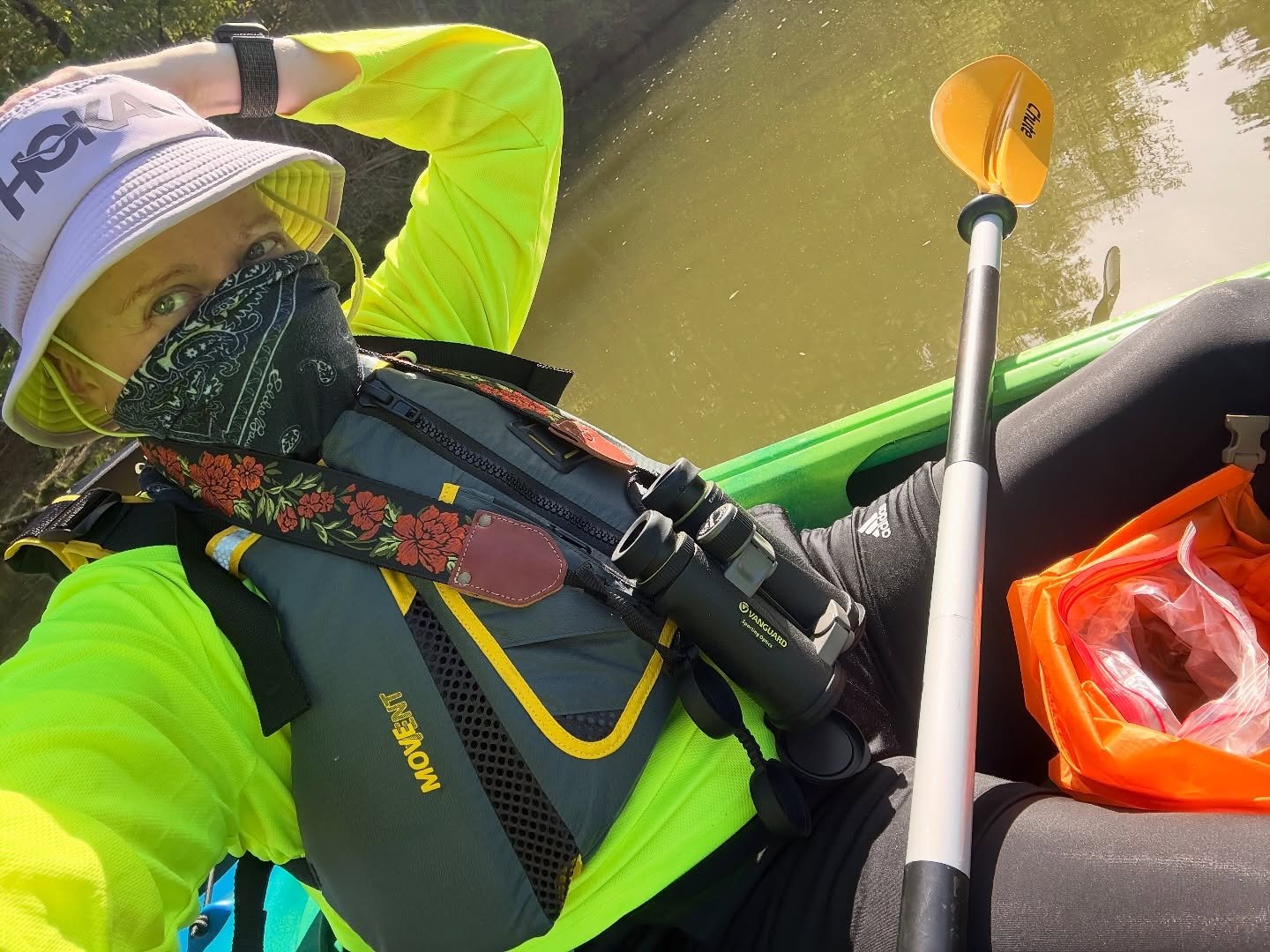 Ended the work week with a paddle and got to float around with the cormorants and turtles. 

Image description: slide 1: person wearing a lavender bucket hat and blue bandana over their mouth and nose floats in a kayak with binoculars 
Slide 2: deck 