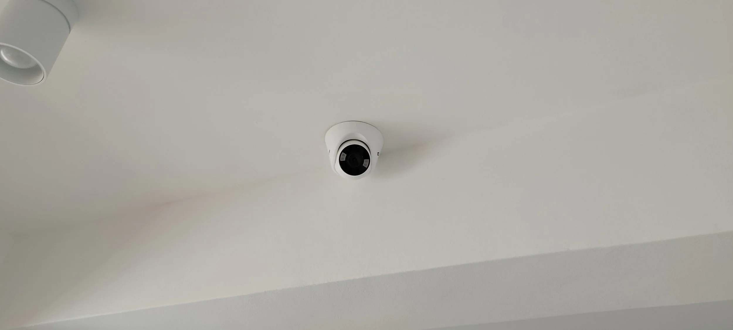 Ceiling-mounted security camera on a white ceiling.