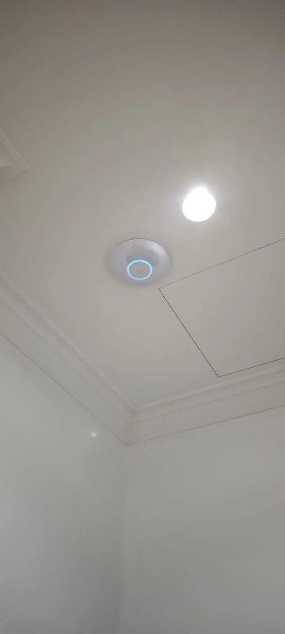 Ceiling with a smoke detector and a ceiling light in a white room.