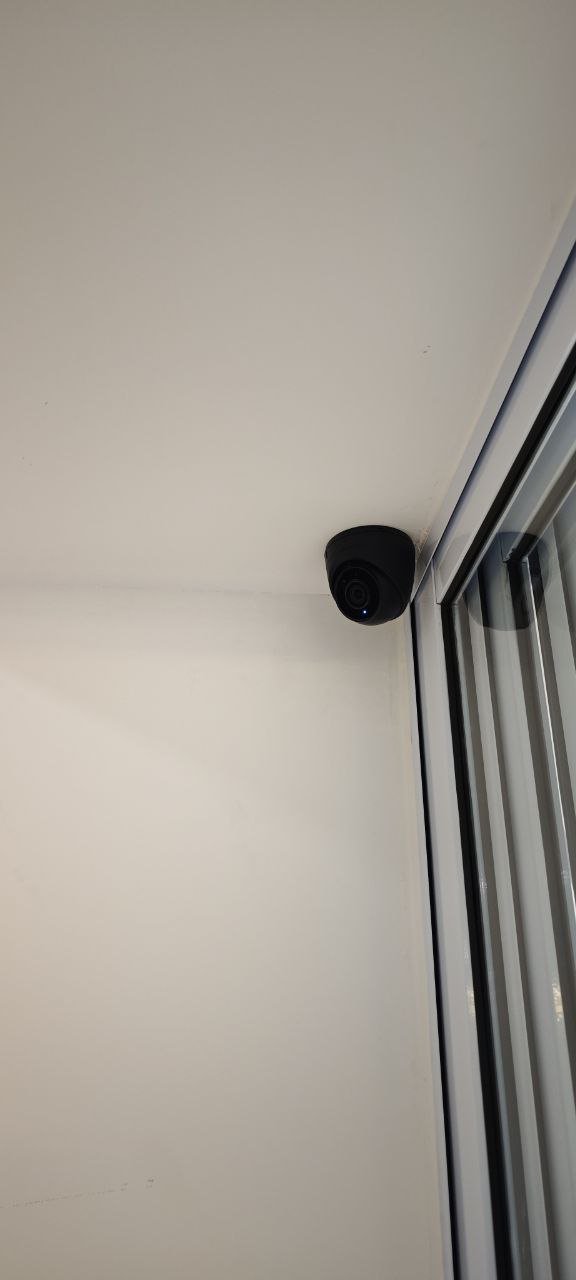 Security camera attached to ceiling near sliding glass door.