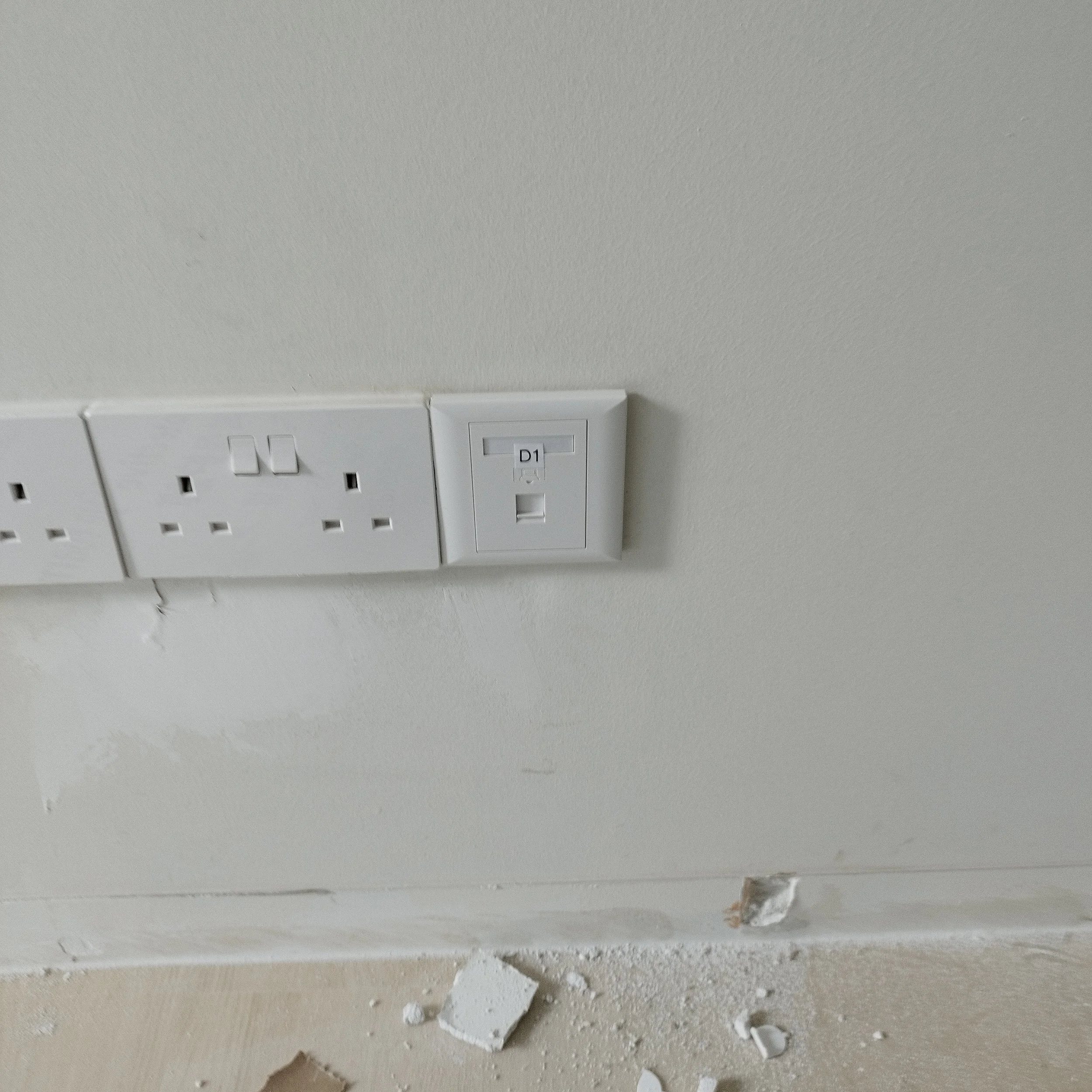 Broken drywall with debris and hole in the wall, near electrical outlet in ceiling