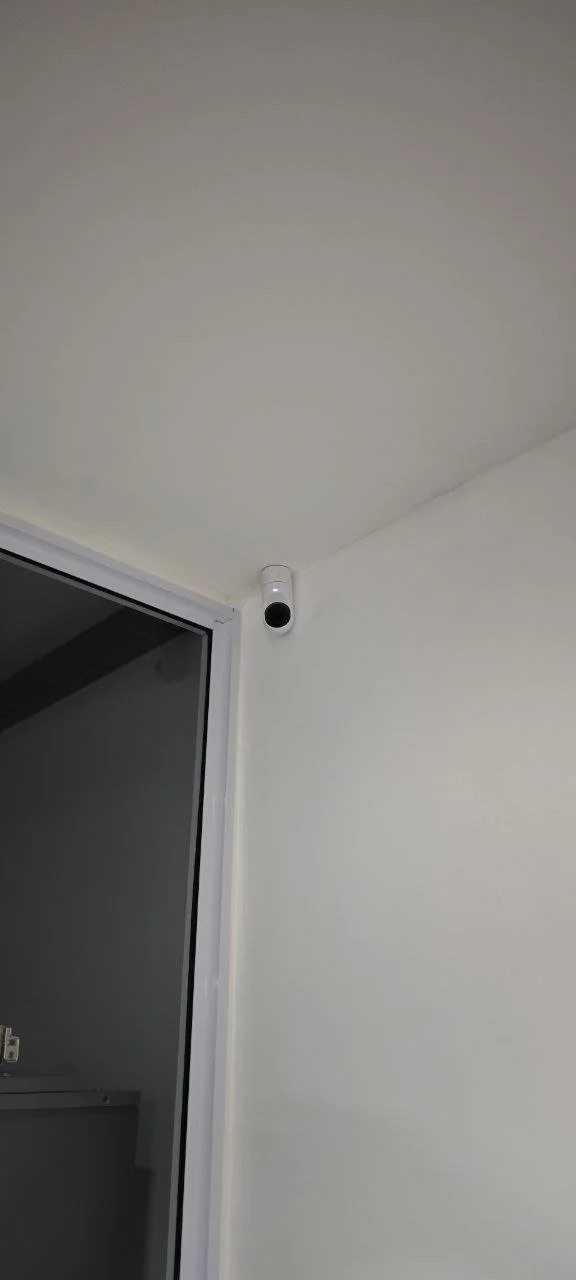 Security camera mounted on white wall near ceiling in a corner of a room.