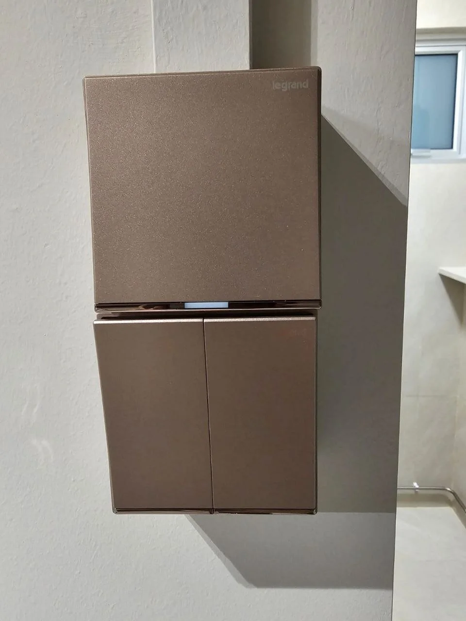 A metallic-colored, two-door Legrand electrical door mounted on a wall