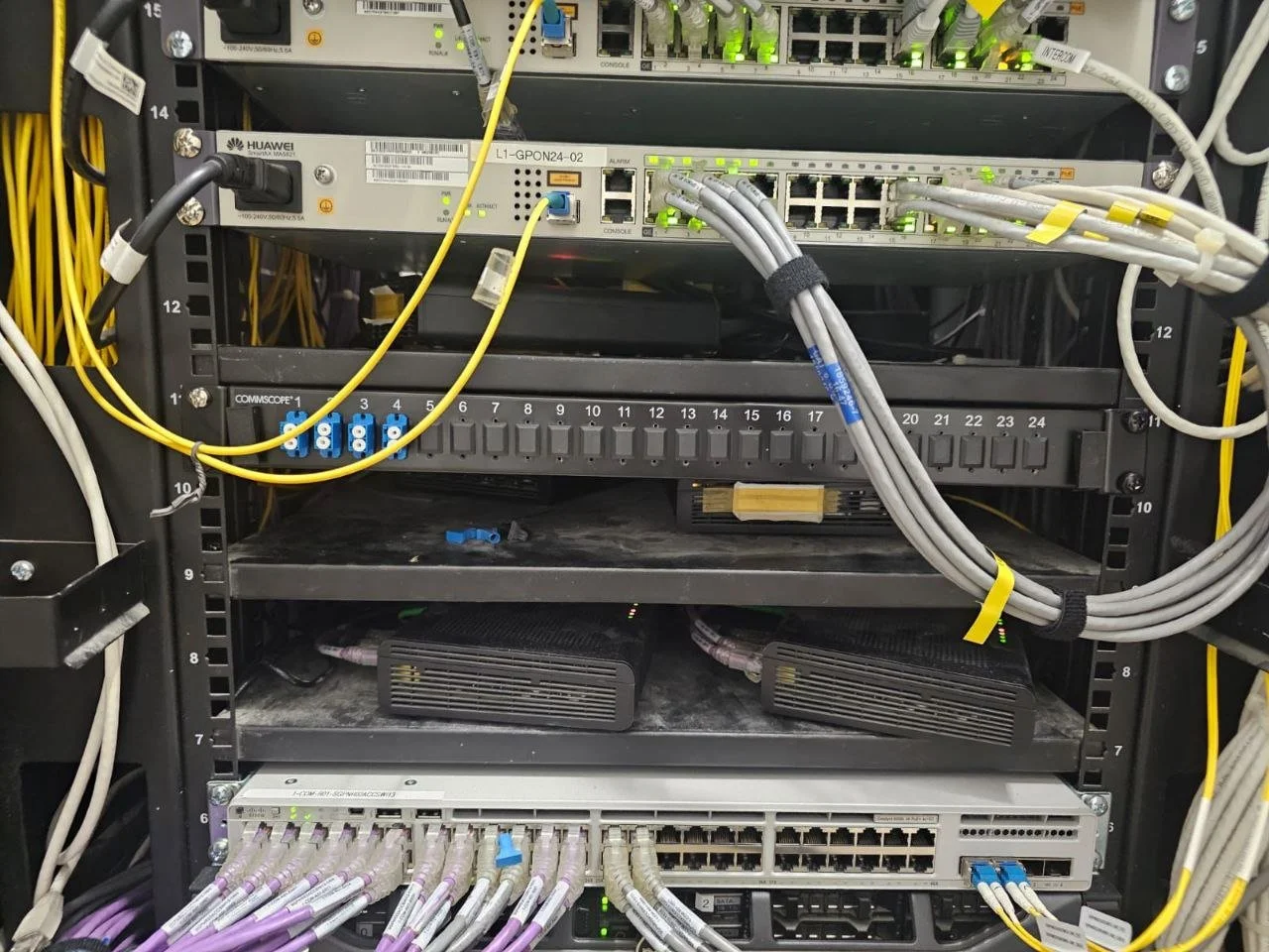 Network server rack with various switches, routers, and network cables connected.