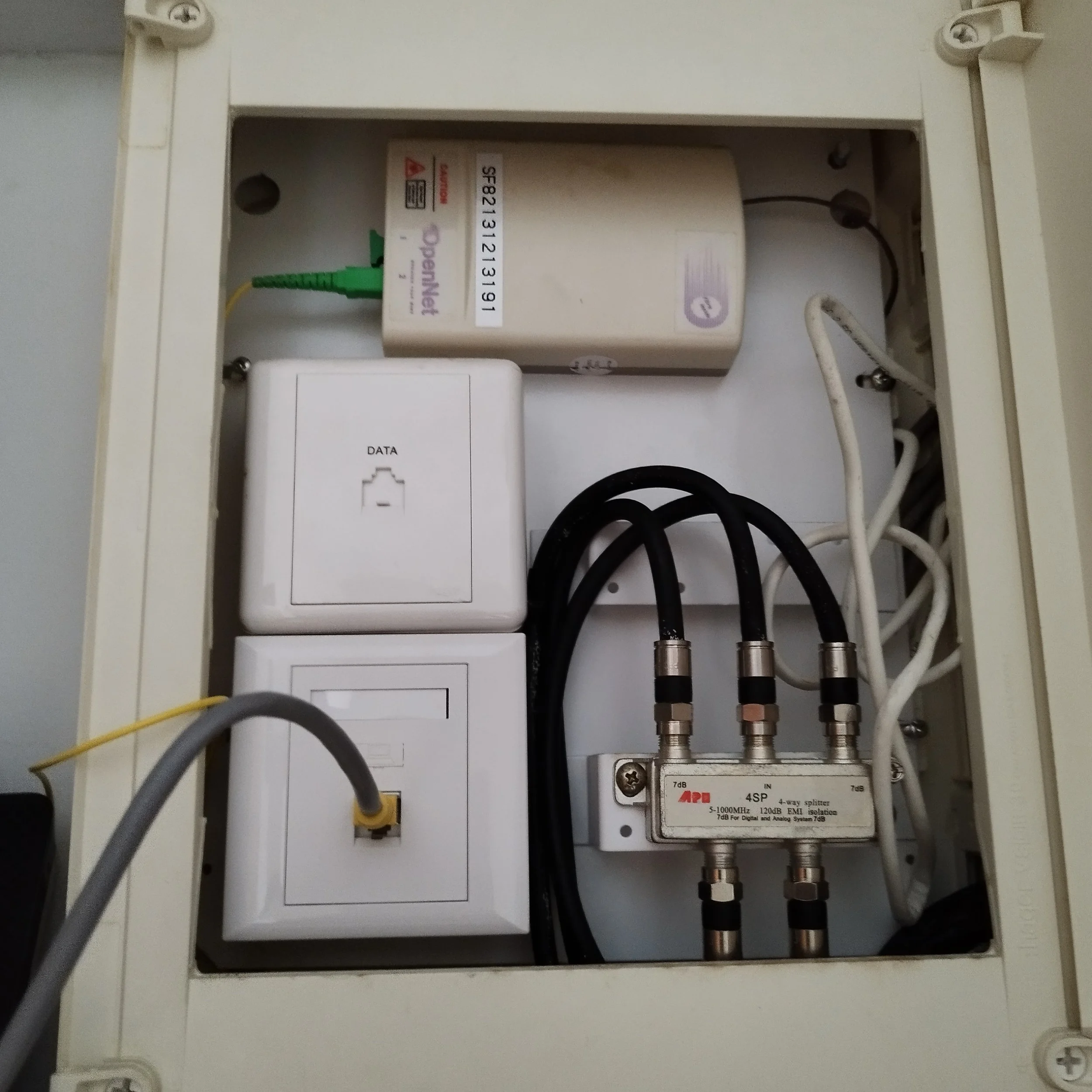 Internal view of an electrical or communication device housing with various cables connected to a circuit board inside a white metal case.