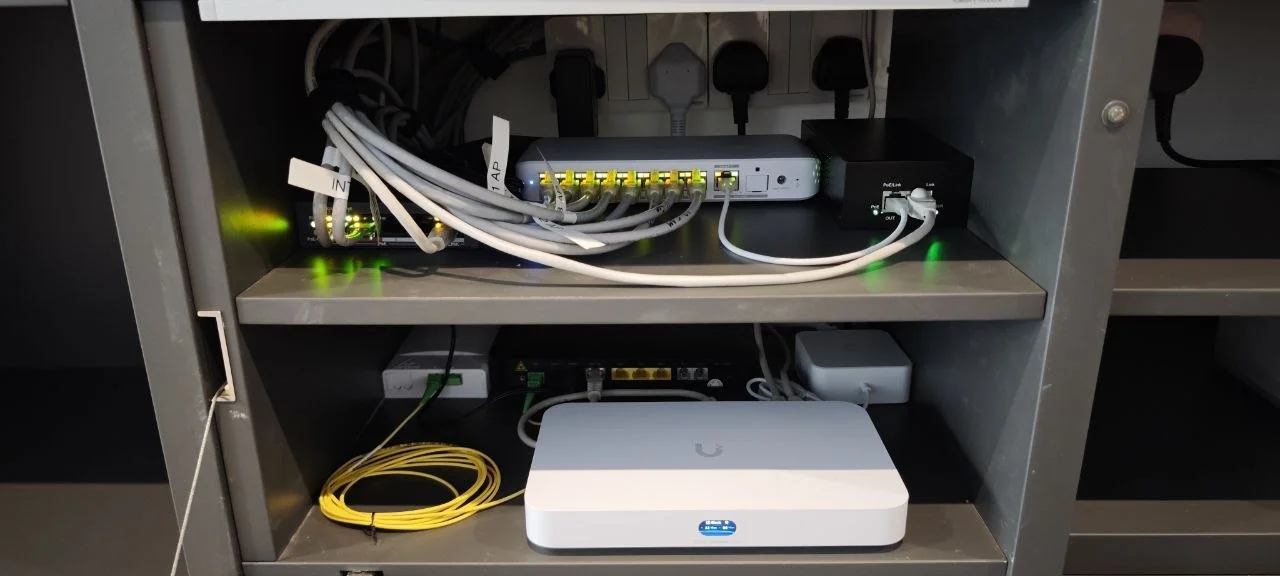 Network equipment and cables on gray shelves in an organized server or network rack.