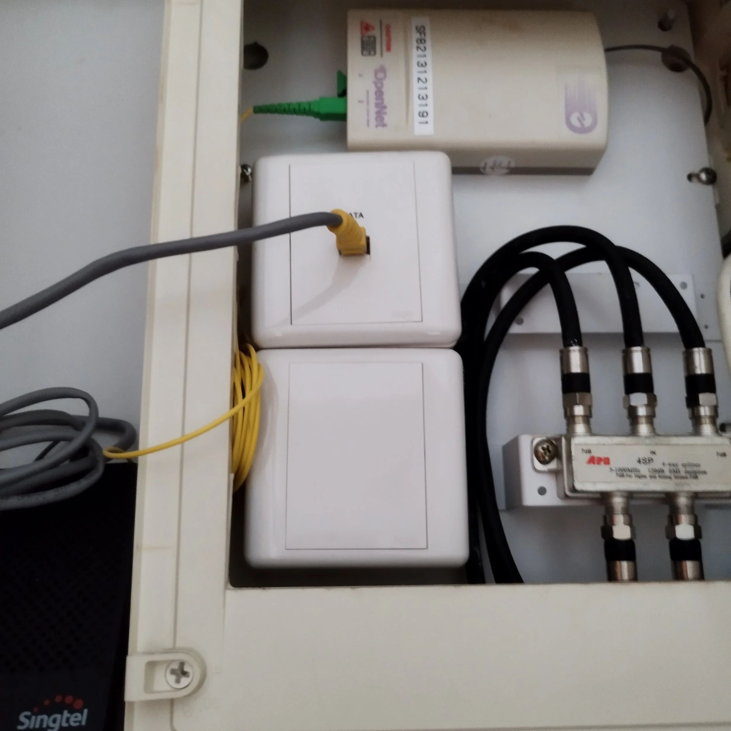 Electrical panel with a white cover, connected to multiple yellow, gray, and black wires, with a green wire plugged in, and an ABB Siemens circuit breaker.
