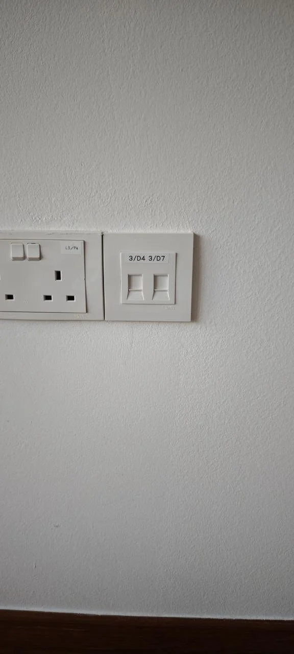 Wall with electrical outlets and switches, including a UK power socket and a switch labeled '3/D4 3/D7'.
