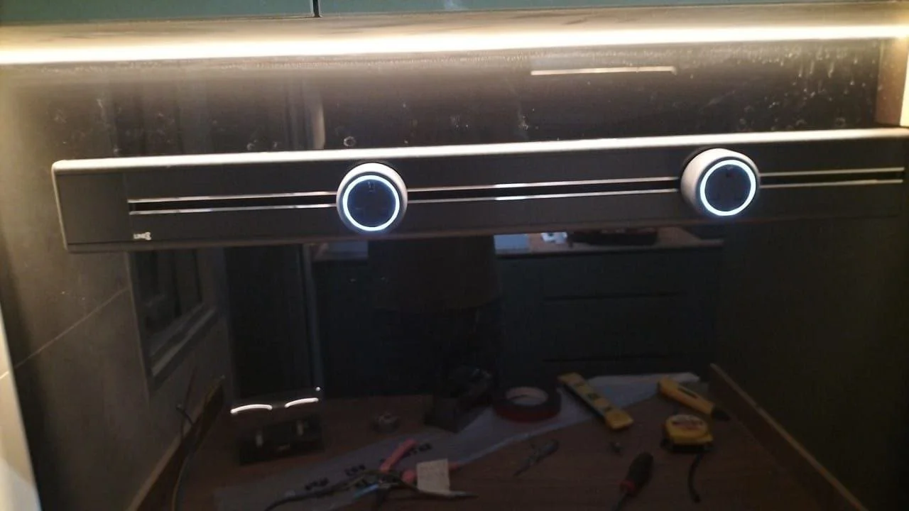 The image shows a black stovetop with two control knobs, with tools and supplies on a work surface below.