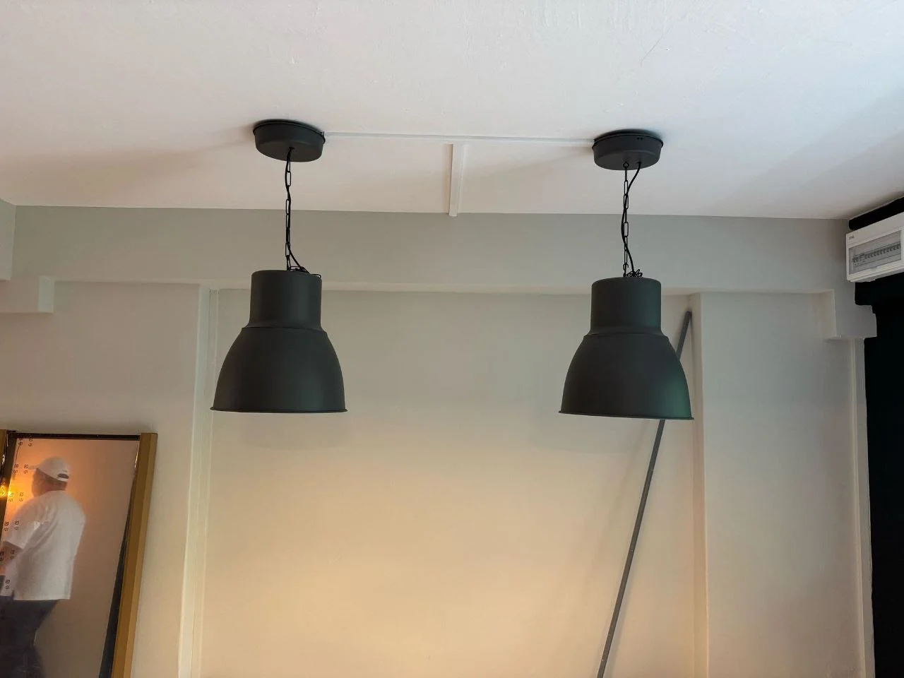 Two black pendant lights hanging from a white ceiling in a modern interior.