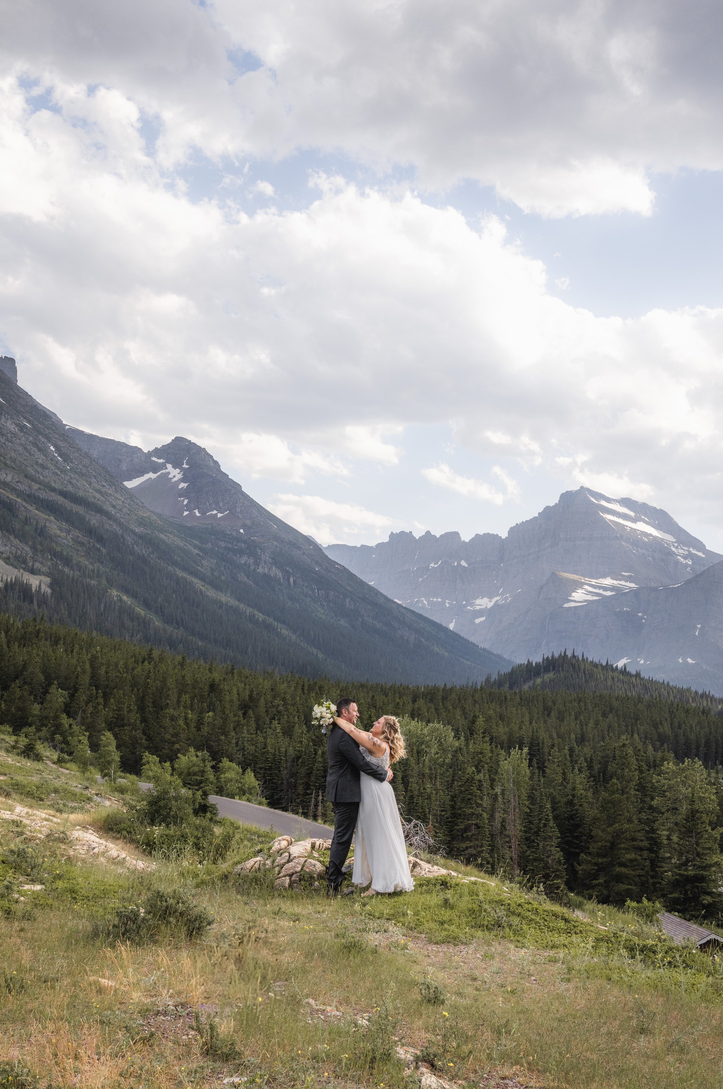 photo of elopement in beautiful glacier national park of bridge and groom together with the forest trees and mountains in the back