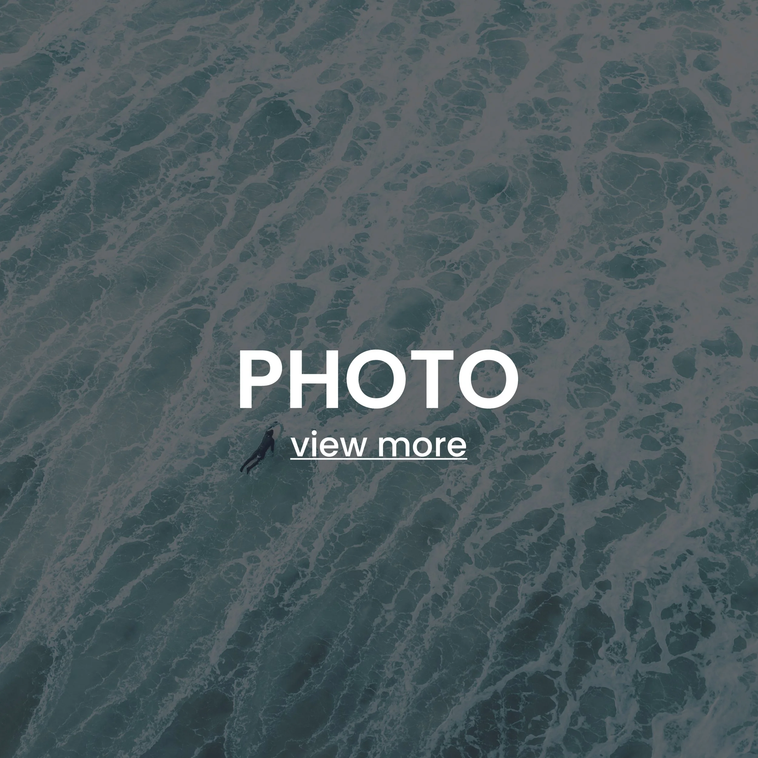 Aerial view of ocean waves with one surfer paddling in the water.