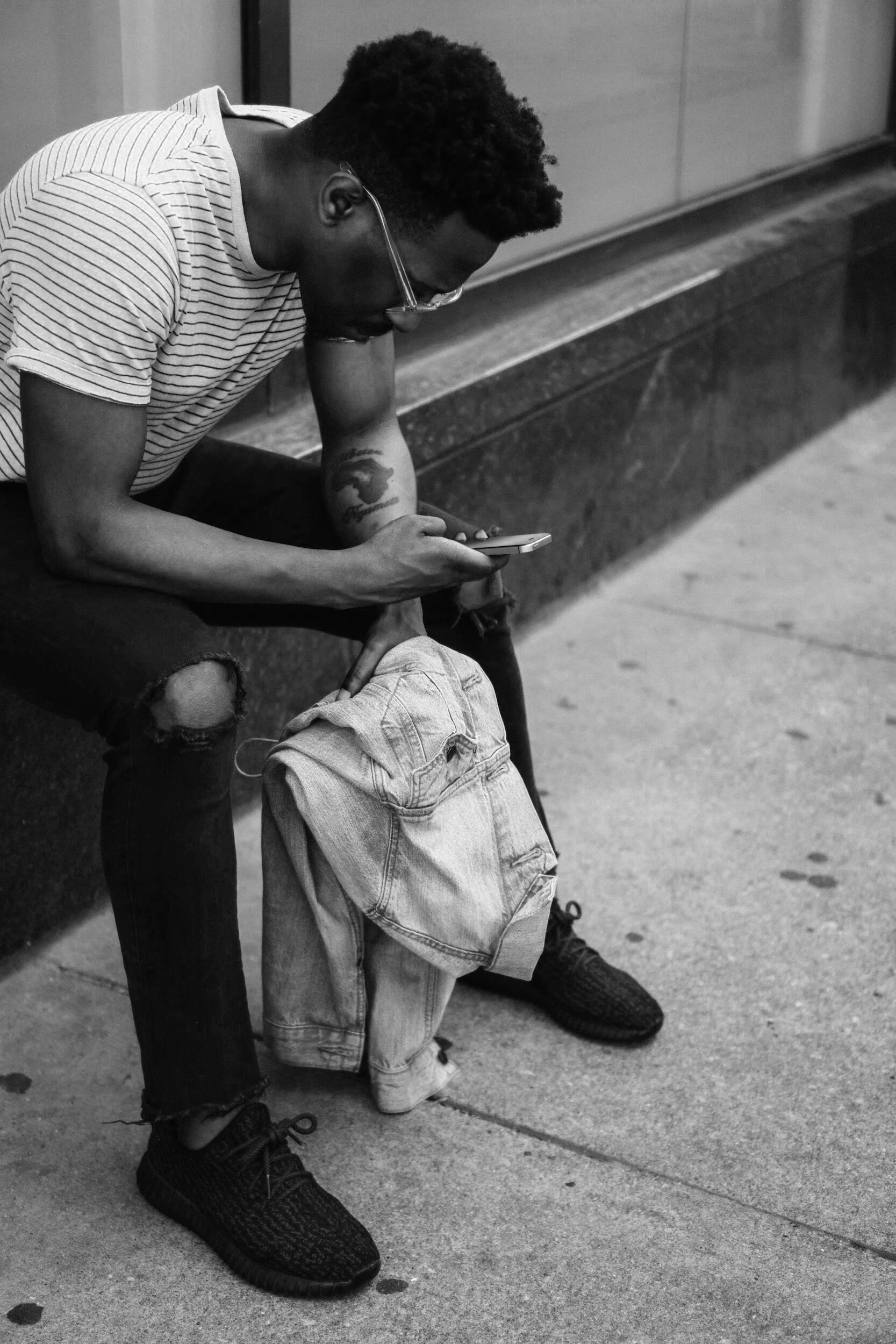 black and white image man looking at cell phone holding coat