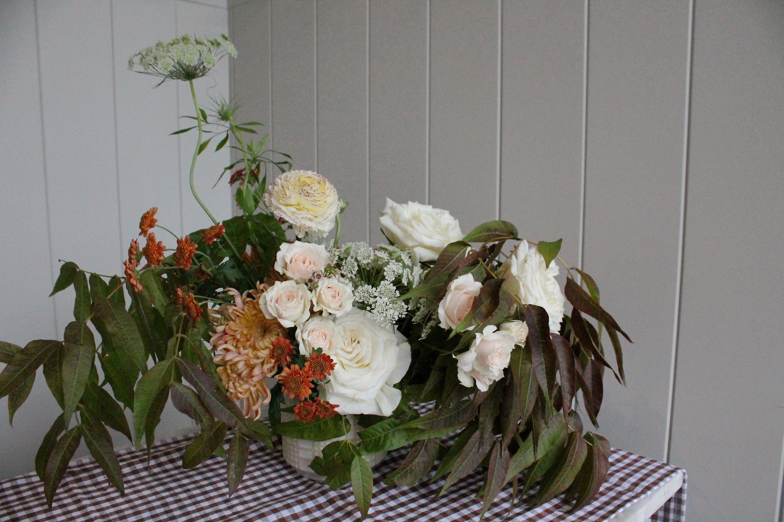 Low view of the neutral Thanksgiving centerpiece with cream roses and rust foliage