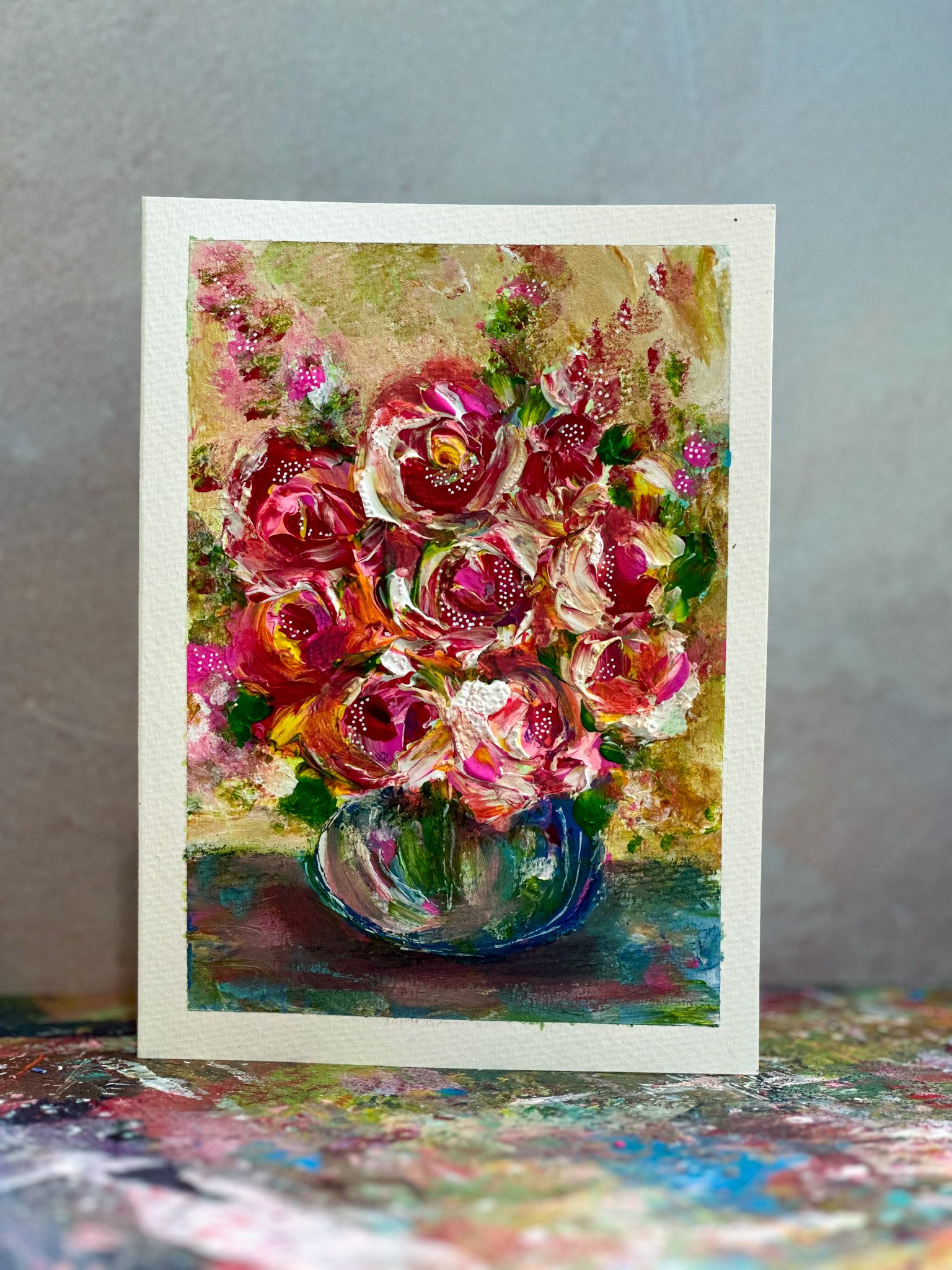 A colorful abstract painting of a flower vase with vibrant pink, red, yellow, and white flowers on a textured background, created with thick brushstrokes.