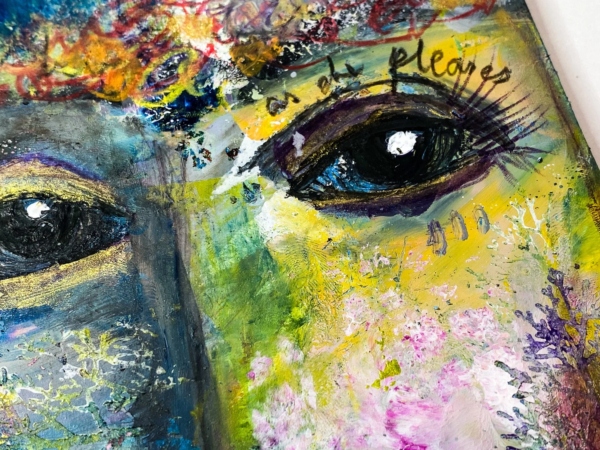 Close-up of a colorful abstract painting featuring a pair of large, expressive eyes with black pupils, surrounded by vibrant splashes of green, yellow, blue, pink, and black paint.