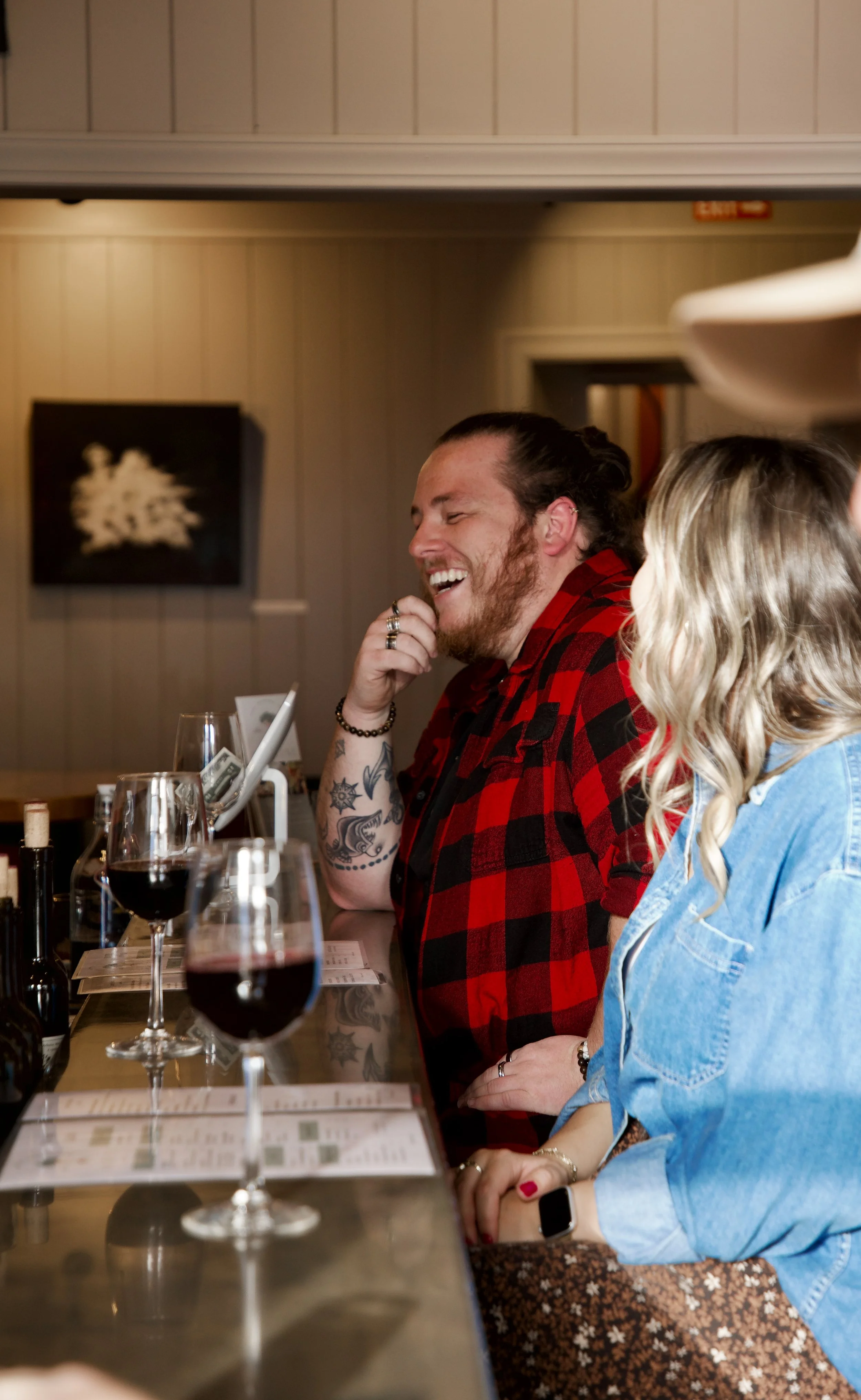 People sitting at a bar enjoying glasses of red wine, smiling and engaging in conversation.