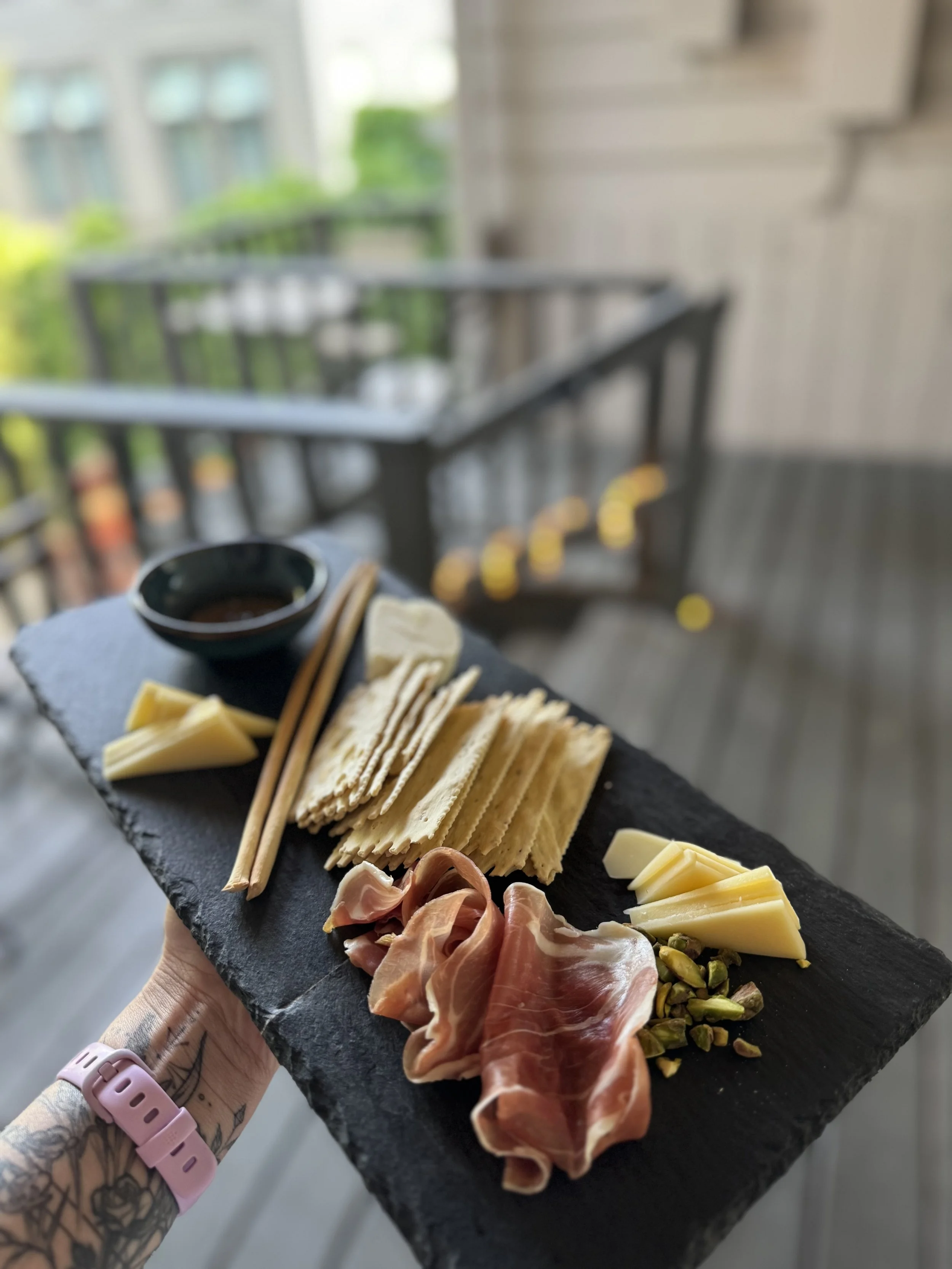 hand holding a charcuterie board with a blue bowl with honey